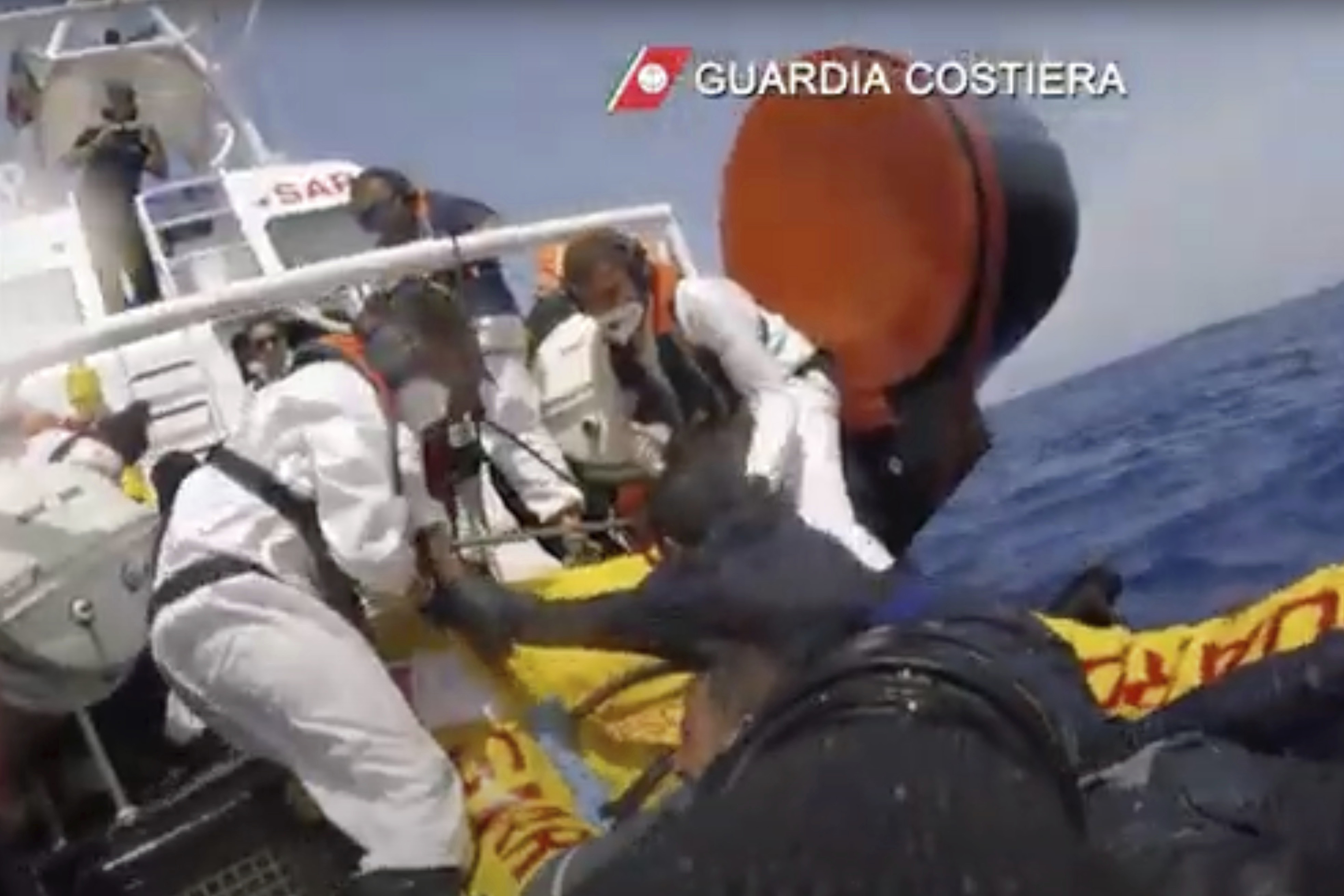 The image made from a video provided by the Italian coast guard shows a patrol boat rescuing migrants from a sinking ship off the coast of Lampedusa, Italy. (Italian Coast Guard via AP)