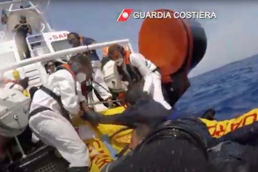 The image made from a video provided by the Italian coast guard shows a patrol boat rescuing migrants from a sinking ship off the coast of Lampedusa, Italy. (Italian Coast Guard via AP)