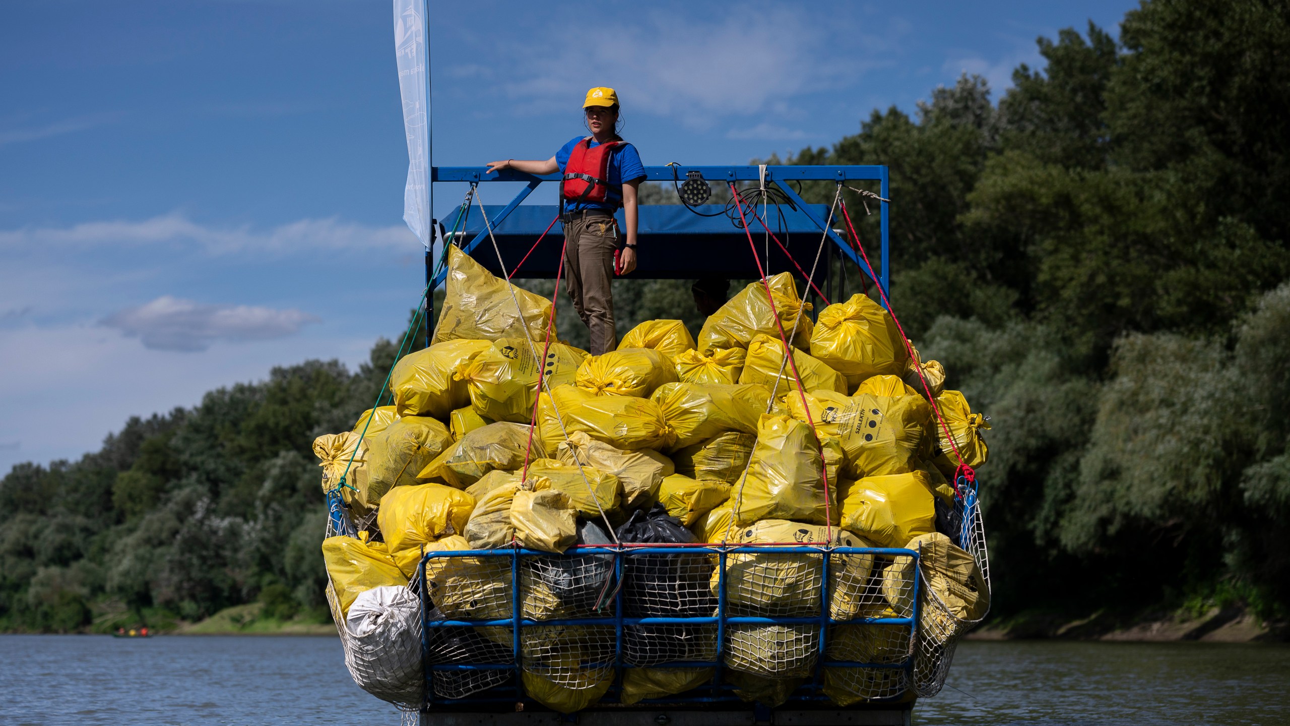 FILE - A volunteer stands on top of a pile of rubbish collected that day while participating in the Plastic Cup event near Tiszaroff, Hungary, Aug. 2, 2023. (AP Photo/Denes Erdos, File)