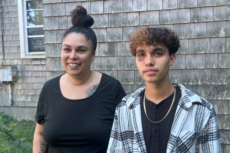 In a photo taken Sept. 4, 2024, in Gloucester, Massachusetts, transgender teenager Jayden Tkaczyk stands outside his house with his mother, Jasmine Tkaczyk. Jayden Tkaczyk alleges that he was beaten up at a party by several other high school students due his being transgender. (AP Photo/Michael Casey)