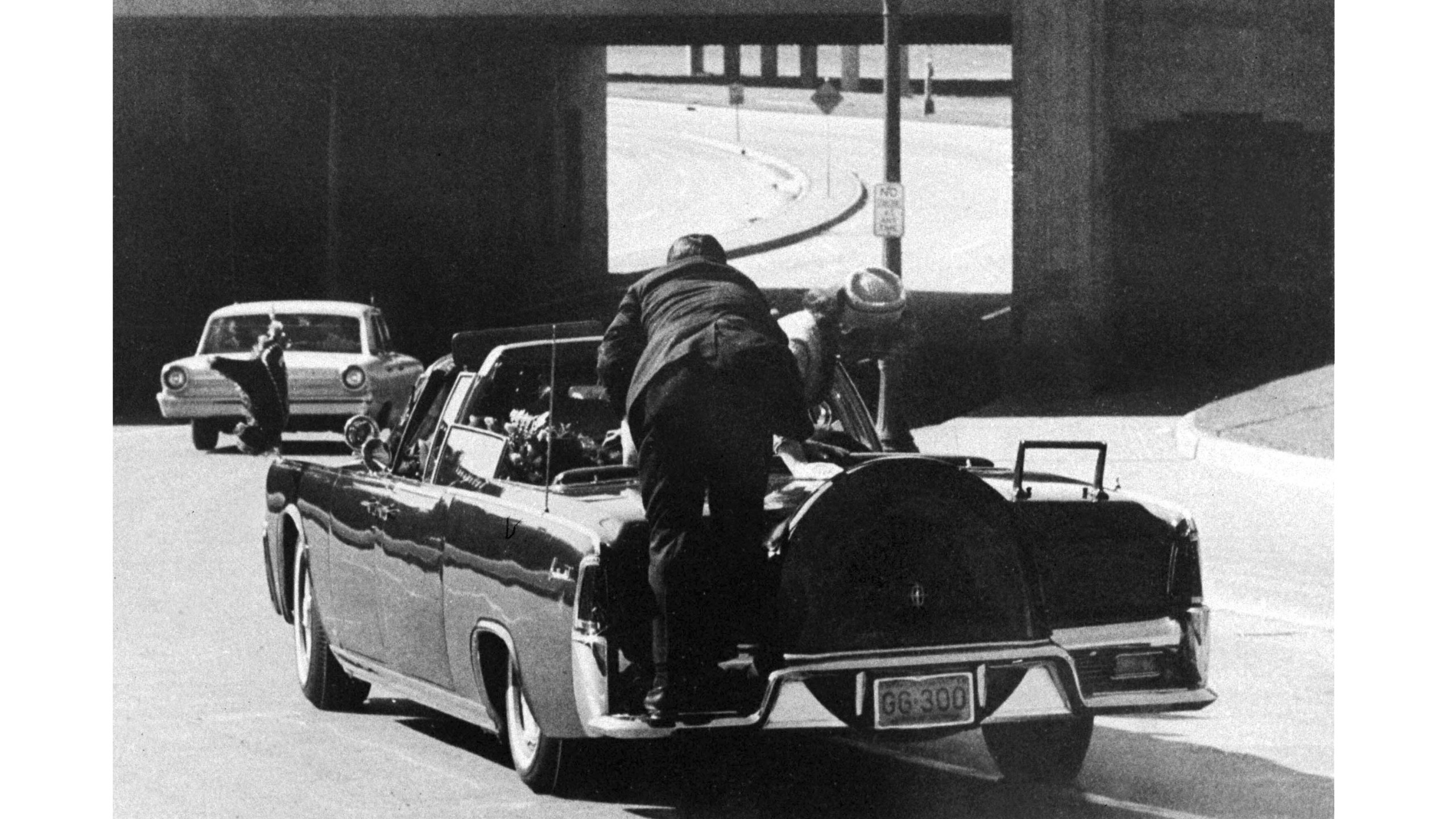 FILE - In this Friday, Nov. 22, 1963 file photo, President John F. Kennedy slumps down in the back seat of the Presidential limousine as it speeds along Elm Street toward the Stemmons Freeway overpass in Dallas after being fatally shot. First lady Jacqueline Kennedy leans over the president as Secret Service agent Clint Hill pushes her back to her seat. (AP Photo/James W. "Ike" Altgens)