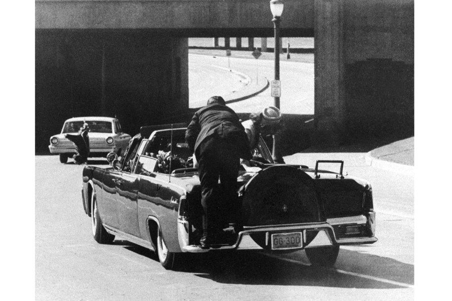 FILE - In this Friday, Nov. 22, 1963 file photo, President John F. Kennedy slumps down in the back seat of the Presidential limousine as it speeds along Elm Street toward the Stemmons Freeway overpass in Dallas after being fatally shot. First lady Jacqueline Kennedy leans over the president as Secret Service agent Clint Hill pushes her back to her seat. (AP Photo/James W. "Ike" Altgens)