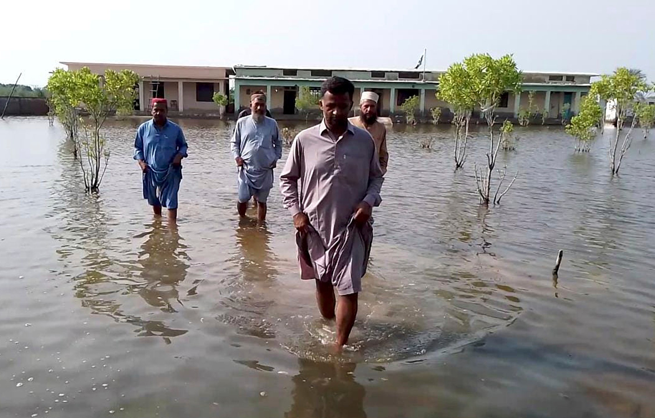 Villagers wade through flood area caused by heavy monsoon rains near Sohbat Pur, an area of Pakistan's southwestern Baluchistan province, Monday, Aug. 19, 2024. (AP Photo)