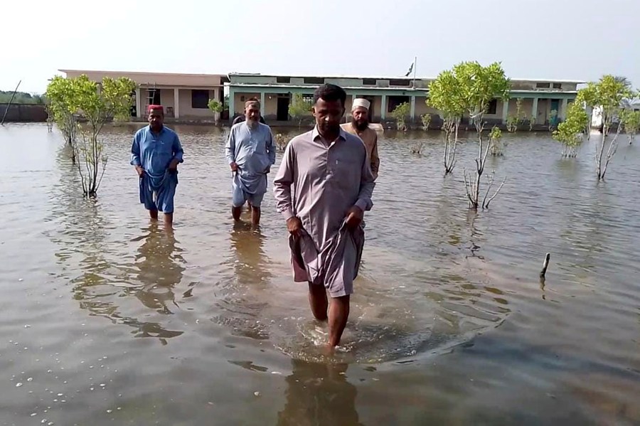 Villagers wade through flood area caused by heavy monsoon rains near Sohbat Pur, an area of Pakistan's southwestern Baluchistan province, Monday, Aug. 19, 2024. (AP Photo)