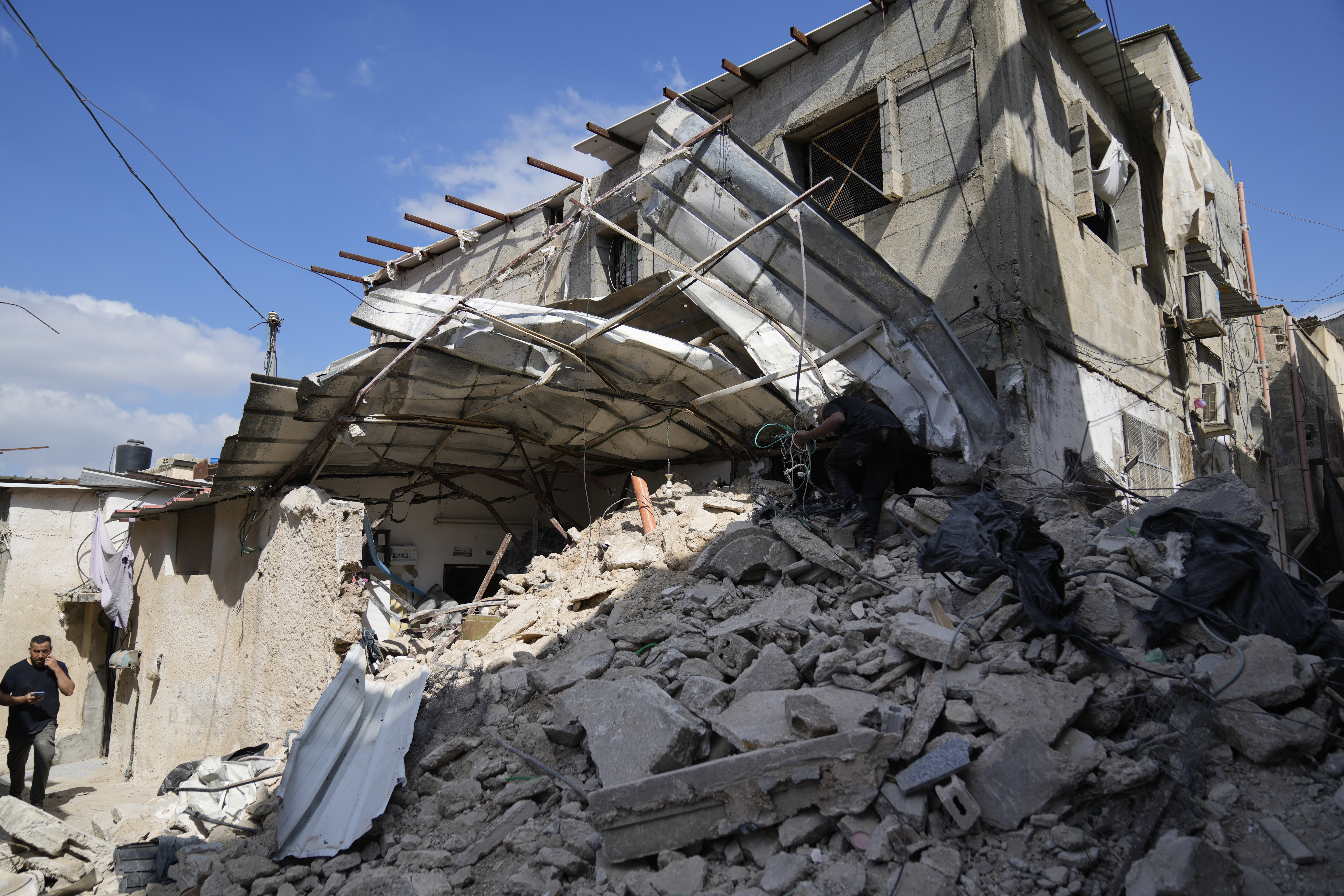 A Palestinian refugee saves some belongings from his families house that was destroyed during the Israeli army operation in the West Bank refugee camp of Tulkarem, in Tulkarem, Thursday, Sept. 5, 2024. (AP Photo/Nasser Nasser)