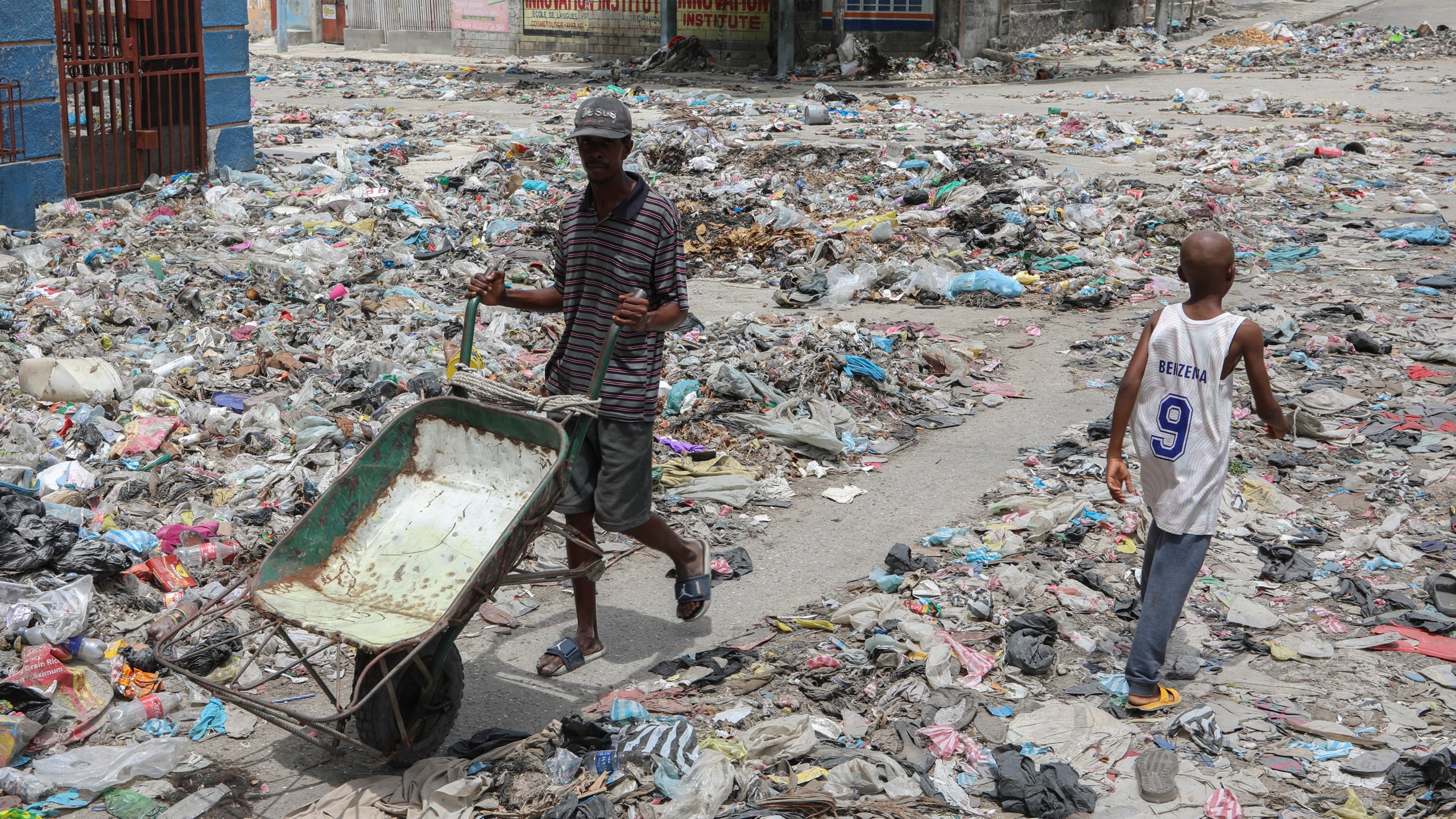 People walk down a street covered with trash in downtown Port-au-Prince, Haiti, Thursday, Sept. 5, 2024. (AP Photo/Odelyn Joseph)