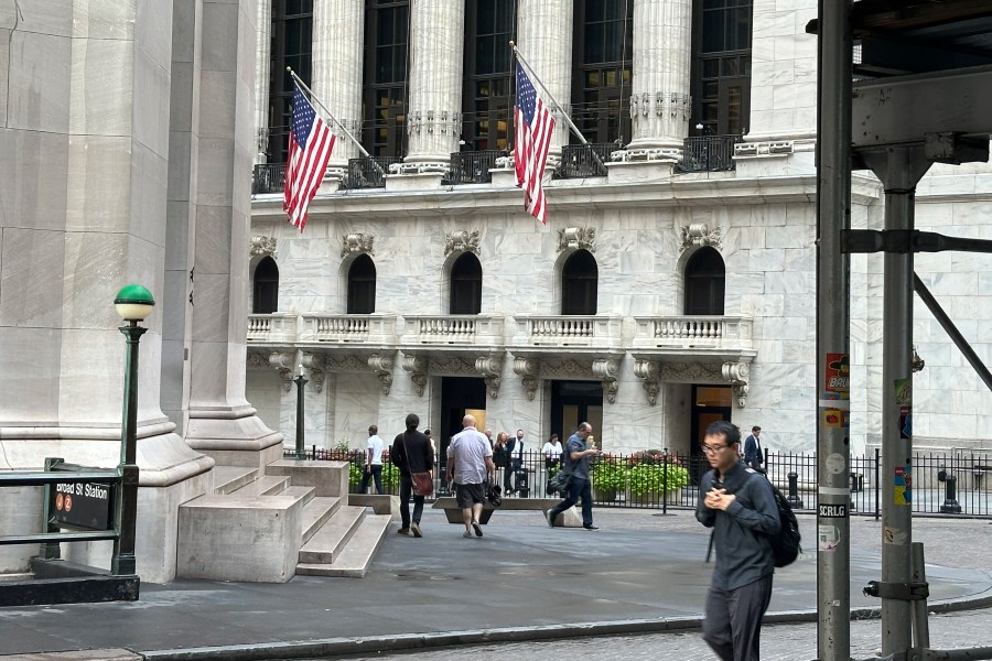 FILE - People pass the New York Stock Exchange, at rear, on Aug. 27, 2024, in New York. (AP Photo/Peter Morgan, File)