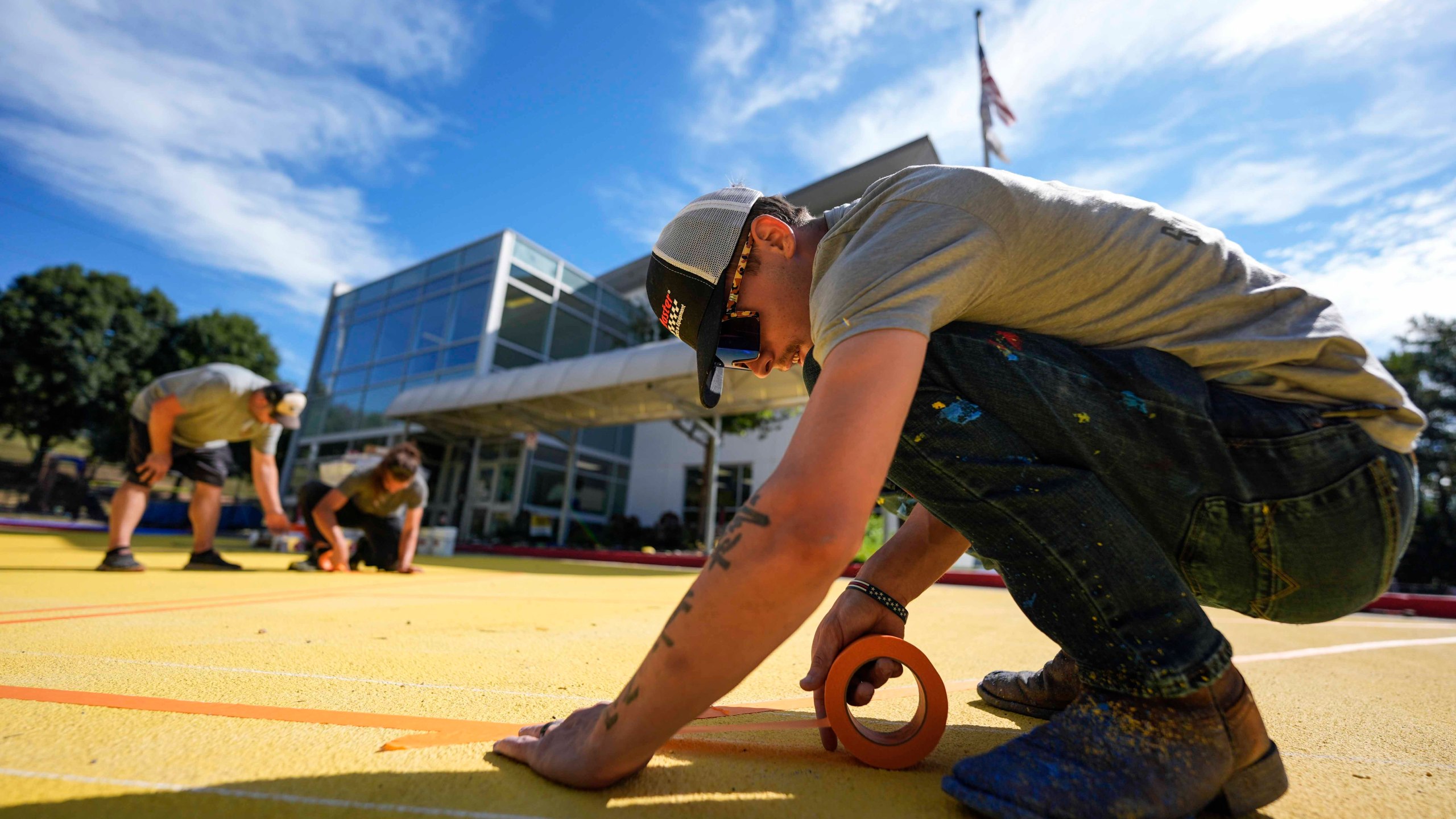 Ronnie Jefferies works on the parking lot at Science, Arts and Entrepreneurship School where it is being repainted to help cool it by making it more reflective, Wednesday, Sept. 4, 2024, in Mableton, Ga. (AP Photo/Mike Stewart)