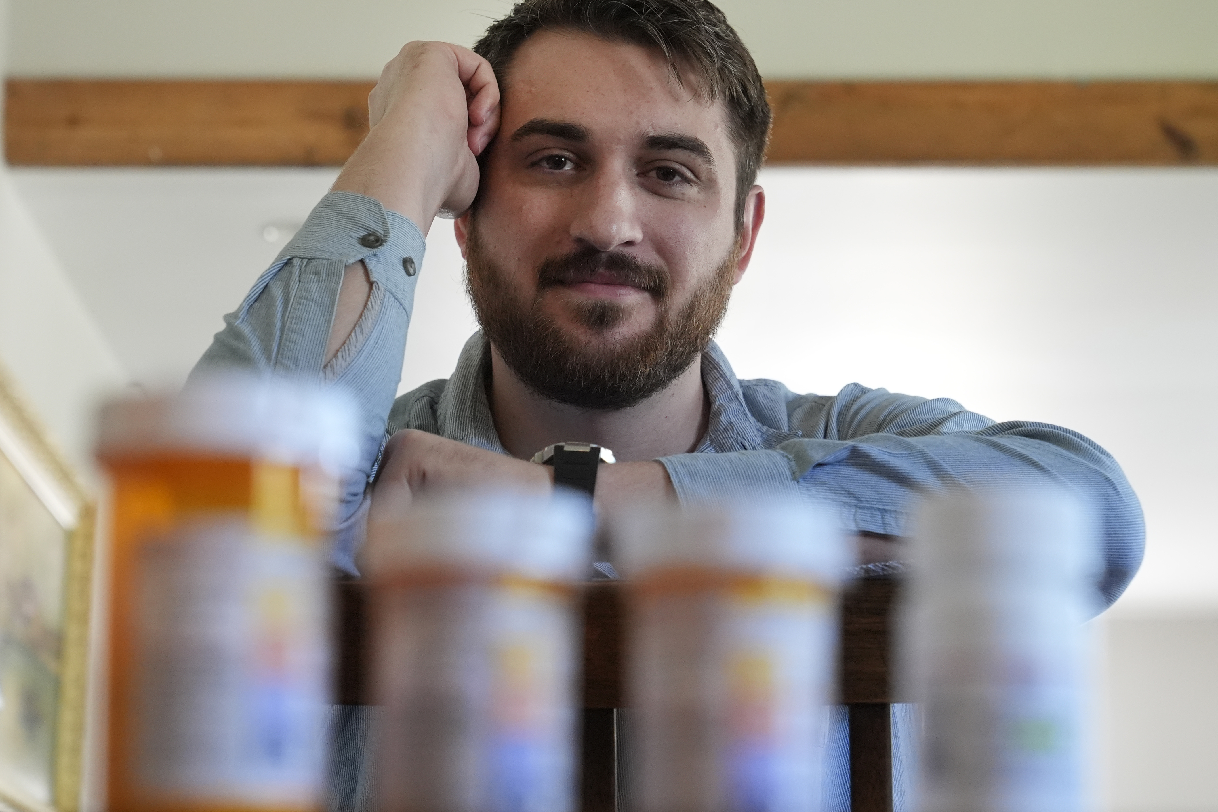 Cancer patient Steven Manetta sits for a portrait Monday, Sept. 9, 2024, in his Lemont, Ill., home with four of the five medicines he takes daily to battle the nausea from his chemotherapy. (AP Photo/Charles Rex Arbogast)