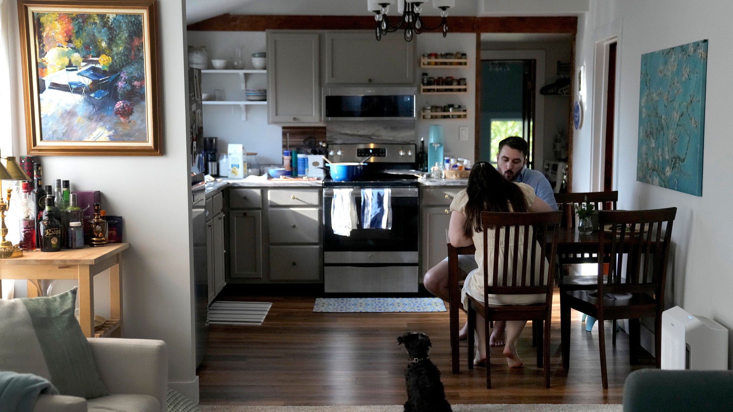 Julia and Steven Manetta eat dinner as their dog, Basil, watches closely Thursday, Aug. 29, 2024, in their Lemont, Ill., home. (AP Photo/Charles Rex Arbogast)