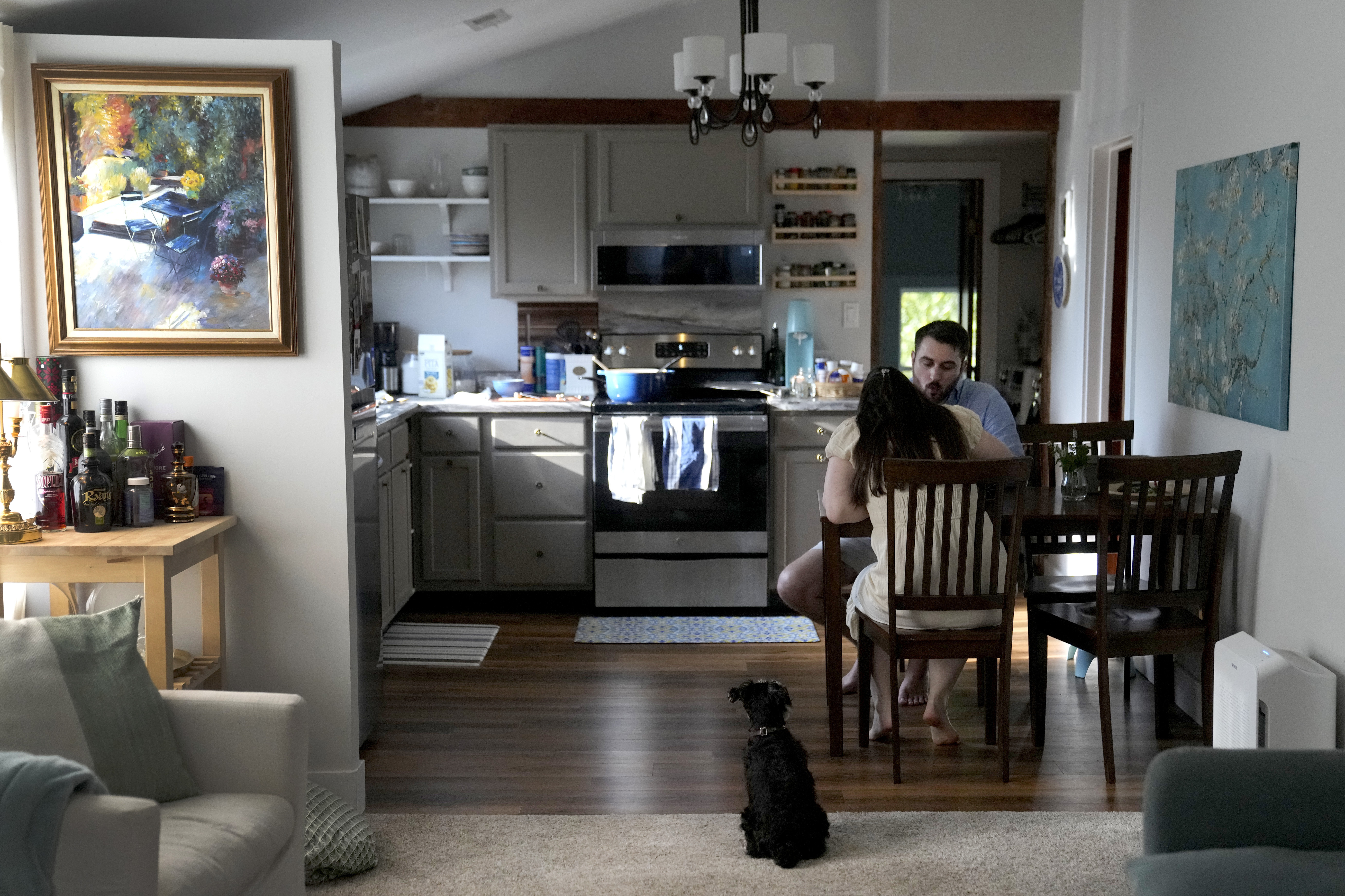 Julia and Steven Manetta eat dinner as their dog, Basil, watches closely Thursday, Aug. 29, 2024, in their Lemont, Ill., home. (AP Photo/Charles Rex Arbogast)