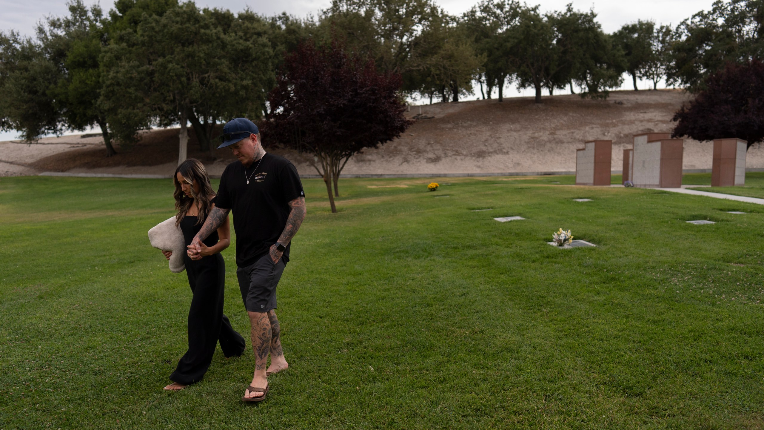 Mikayla Brown, left, and her husband, Tyler, hold hands as they walk toward their car after visiting the grave of their son, Elijah, who died of a fentanyl overdose at 15, in Paso Robles, Calif., Friday, Aug. 2, 2024. (AP Photo/Jae C. Hong)