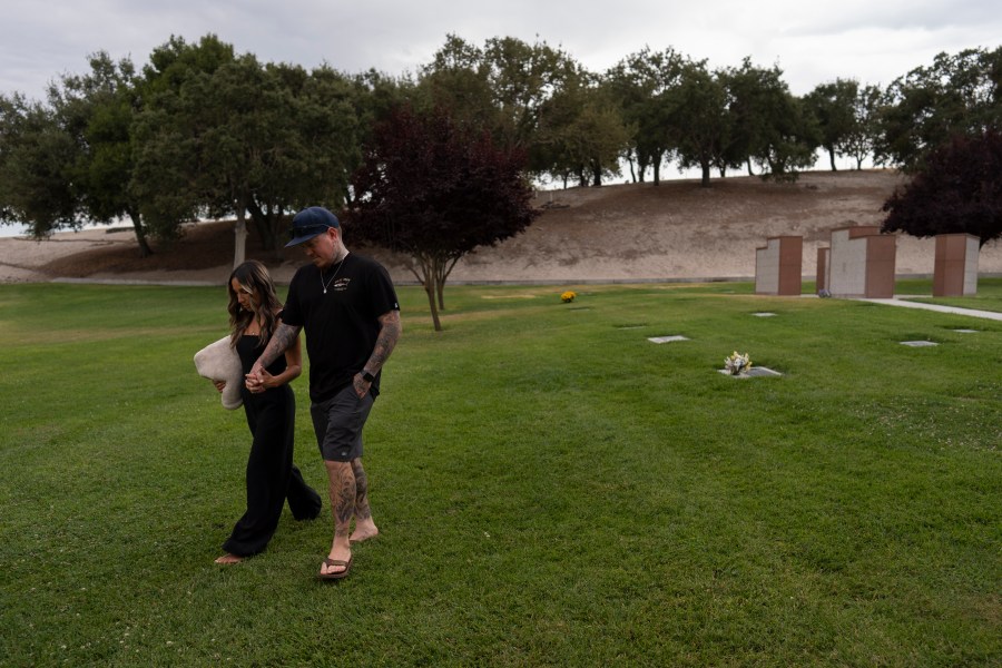 Mikayla Brown, left, and her husband, Tyler, hold hands as they walk toward their car after visiting the grave of their son, Elijah, who died of a fentanyl overdose at 15, in Paso Robles, Calif., Friday, Aug. 2, 2024. (AP Photo/Jae C. Hong)