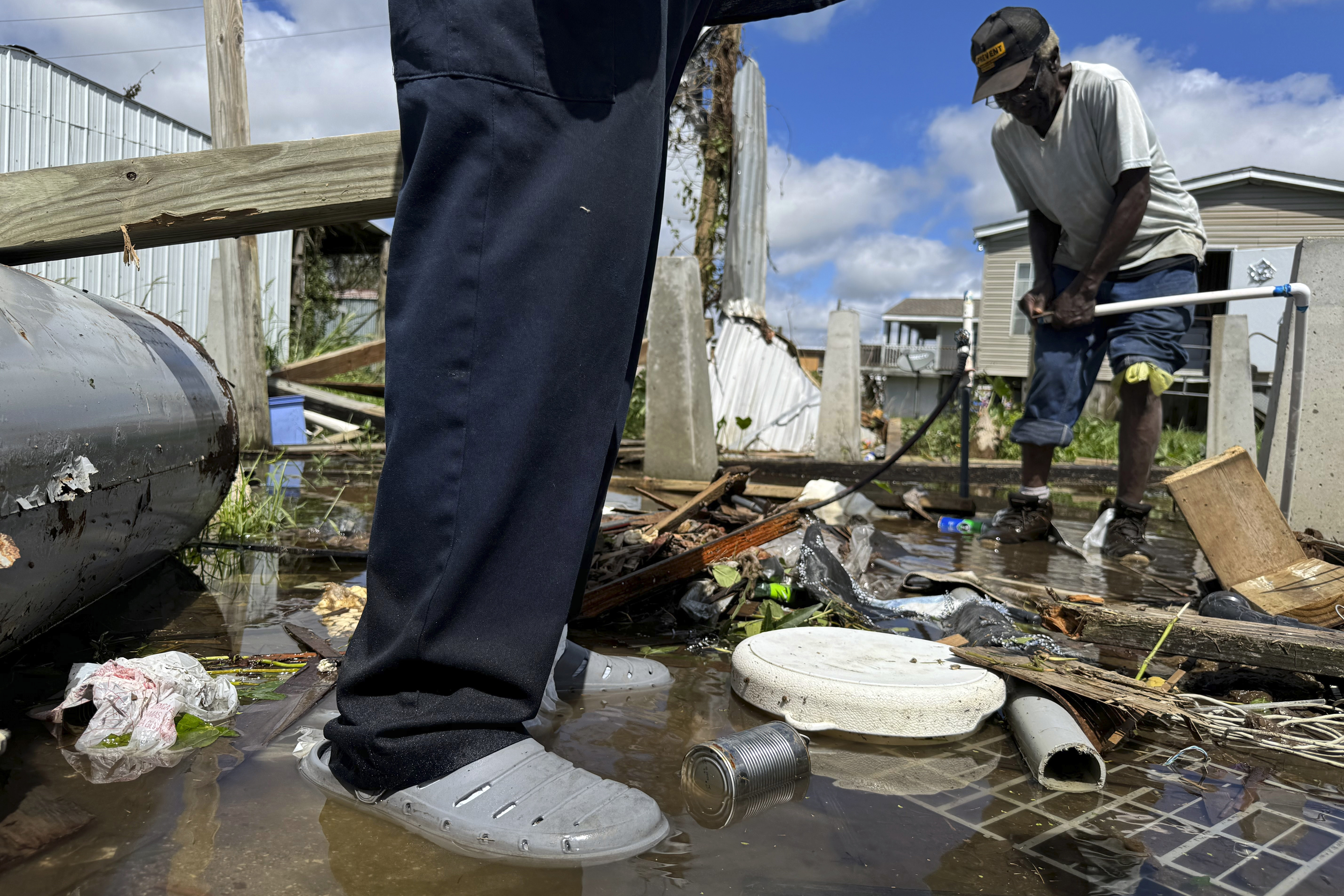 Brothers Wilson Garner, 73, left, and Carter Caldwell, 69, try to fix a broken water pipe, Thursday, Sept. 12, 2024, in Ashland, La., in the aftermath of Hurricane Francine. (AP Photo/Jack Brook)