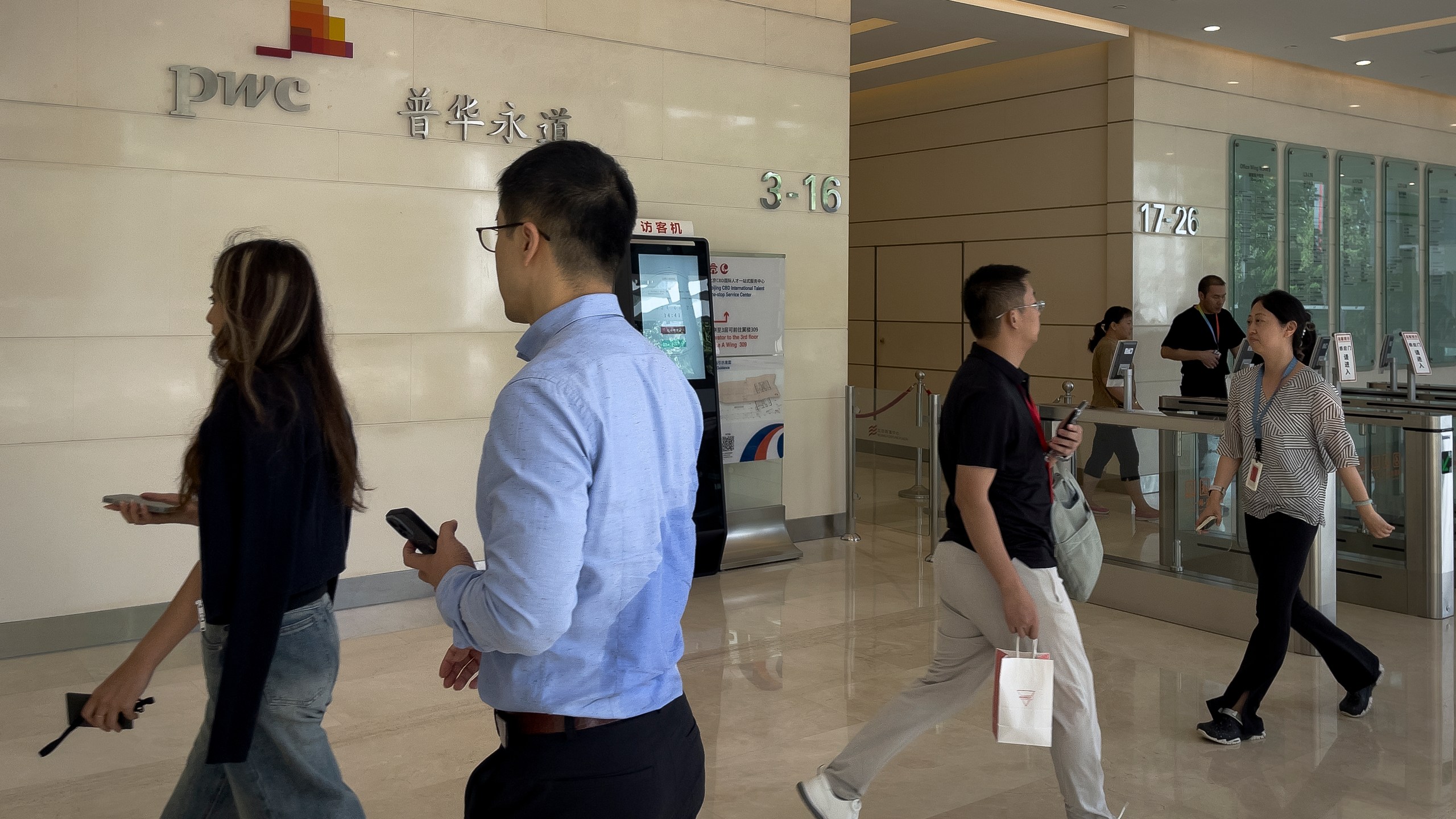 People walk by the audit firm PricewaterhouseCoopers (PWC) office at the Fortune Financial Center in Beijing on Aug. 27, 2024. (AP Photo/Andy Wong)