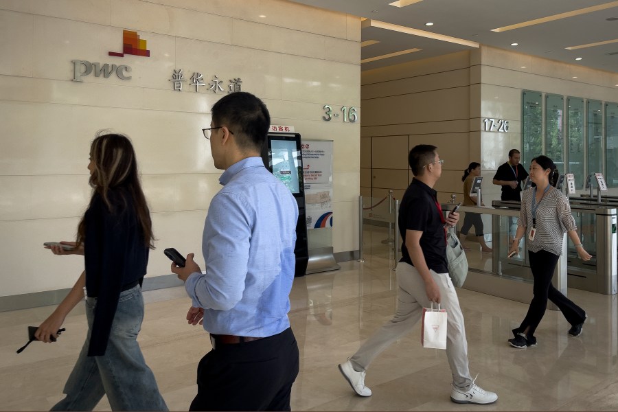 People walk by the audit firm PricewaterhouseCoopers (PWC) office at the Fortune Financial Center in Beijing on Aug. 27, 2024. (AP Photo/Andy Wong)