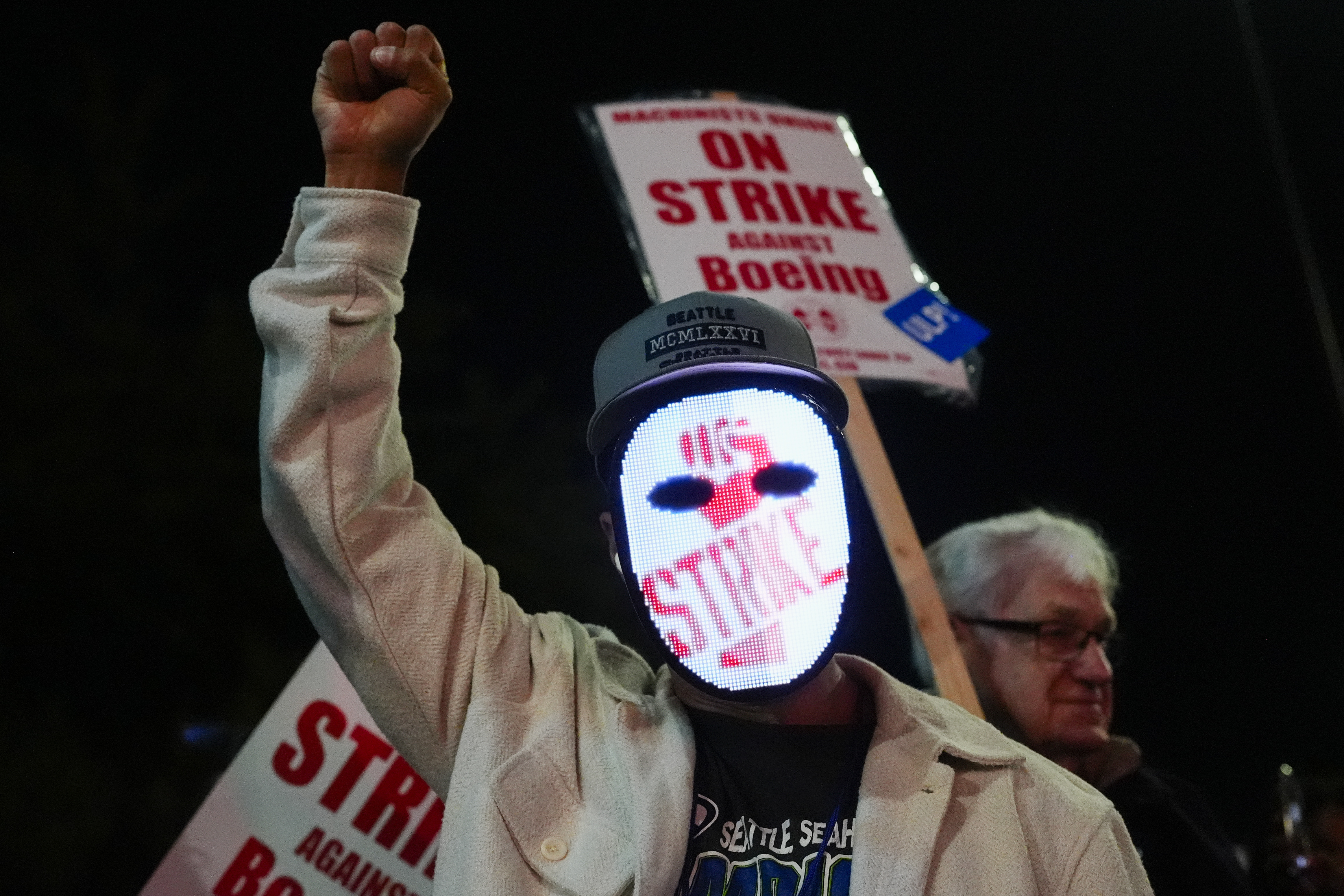 A Boeing worker wears a mask with a digital "strike" sign as employees picket after union members voted overwhelmingly to reject a contract offer and go on strike Friday, Sept. 13, 2024, outside the company's factory in Renton, Wash. (AP Photo/Lindsey Wasson)