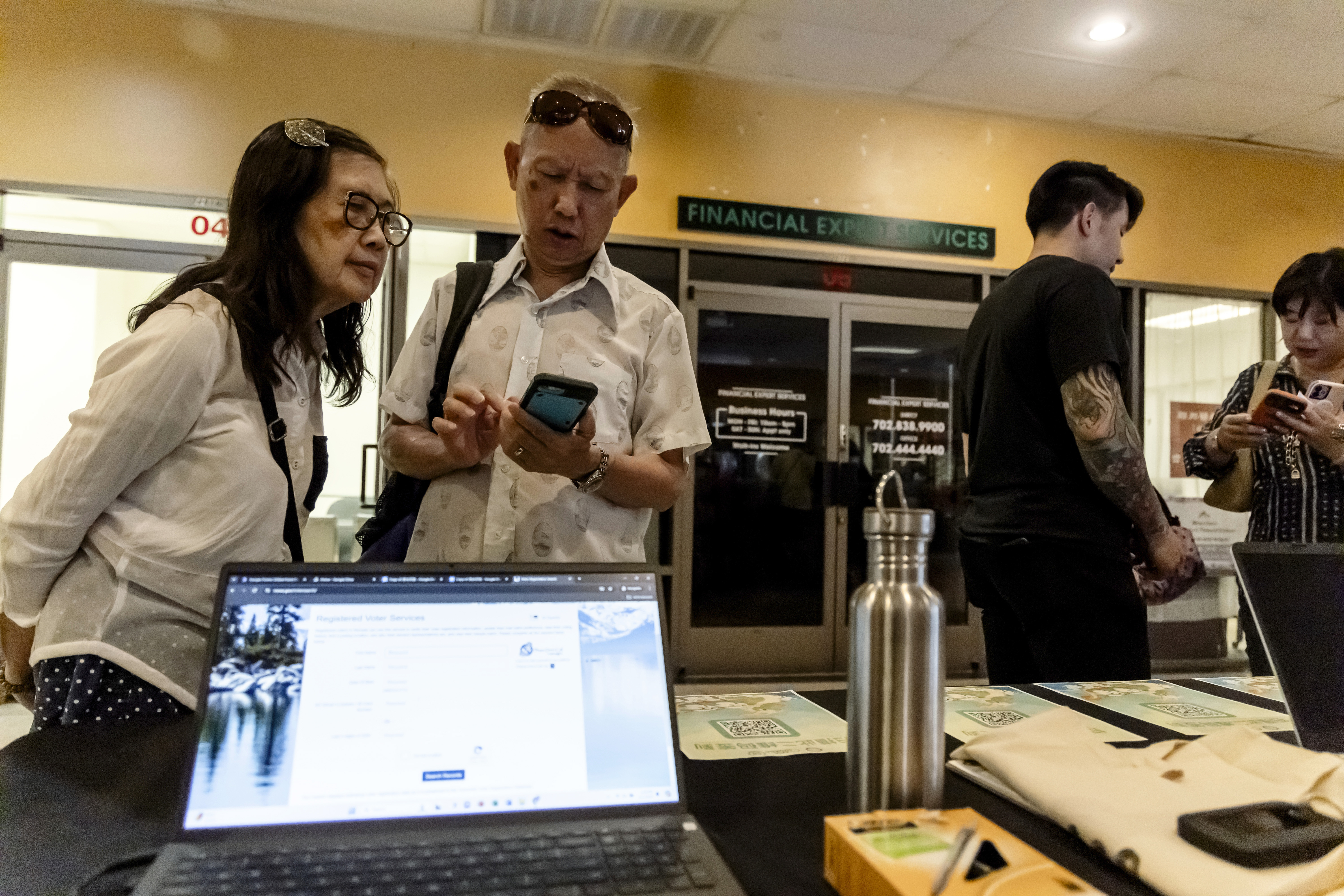 Members of the Las Vegas Asian community scan a QR code taking them to voter information translated into Chinese during the annual Dragon Boat Festival in Las Vegas, Wednesday, June 5, 2024. (Christopher Lomahquahu/News21 via AP)