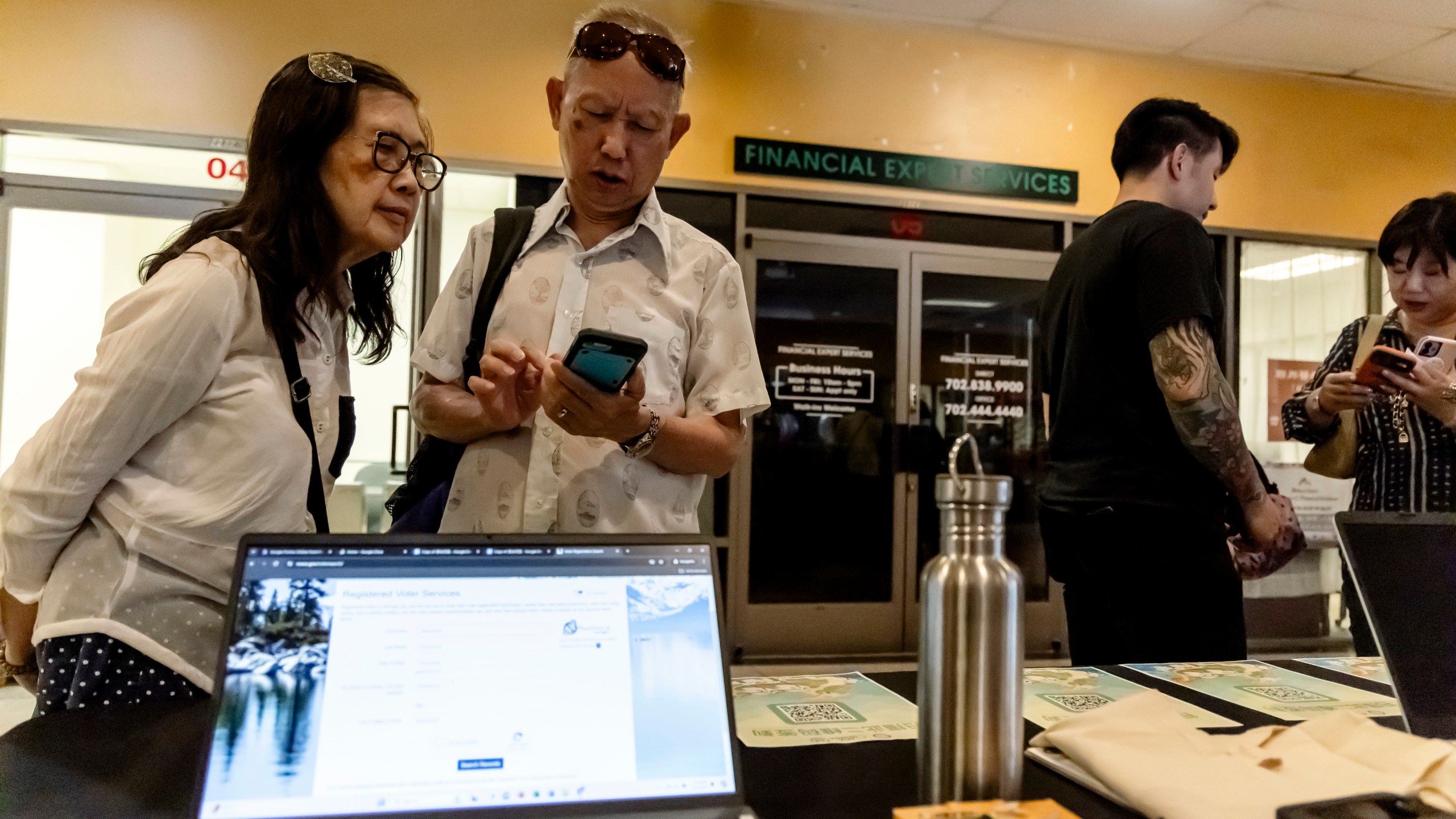 Members of the Las Vegas Asian community scan a QR code taking them to voter information translated into Chinese during the annual Dragon Boat Festival in Las Vegas, Wednesday, June 5, 2024. (Christopher Lomahquahu/News21 via AP)