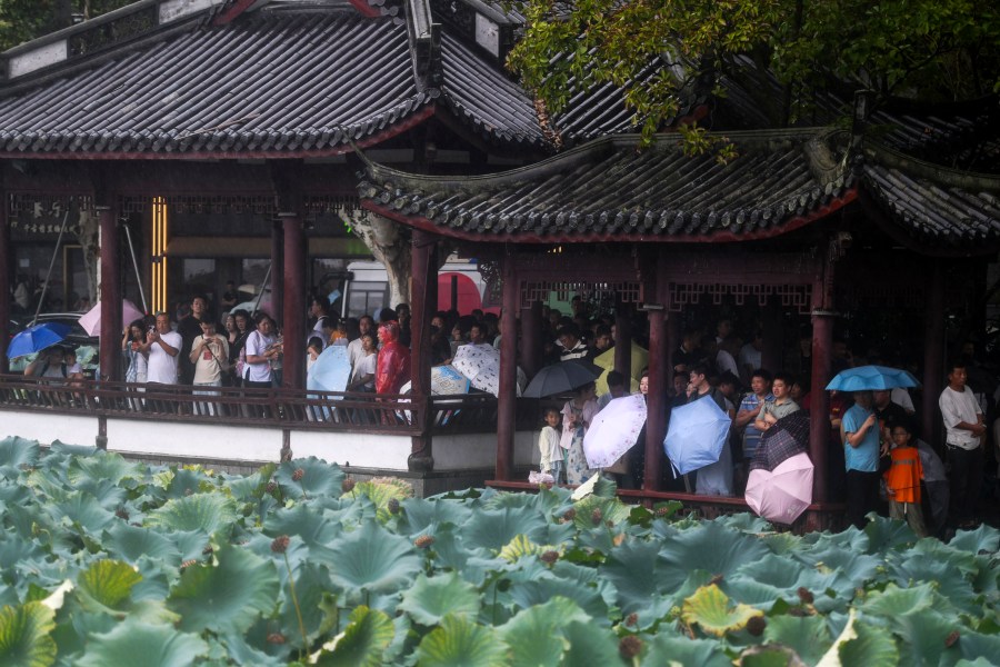 Tourists take shelter in pavilions from the rains brought by Typhoon Bebinca during the Mid-Autumn Festival holiday, in Hangzhou in east China's Zhejiang province, Monday, Sept. 16, 2024. (Chinatopix Via AP)