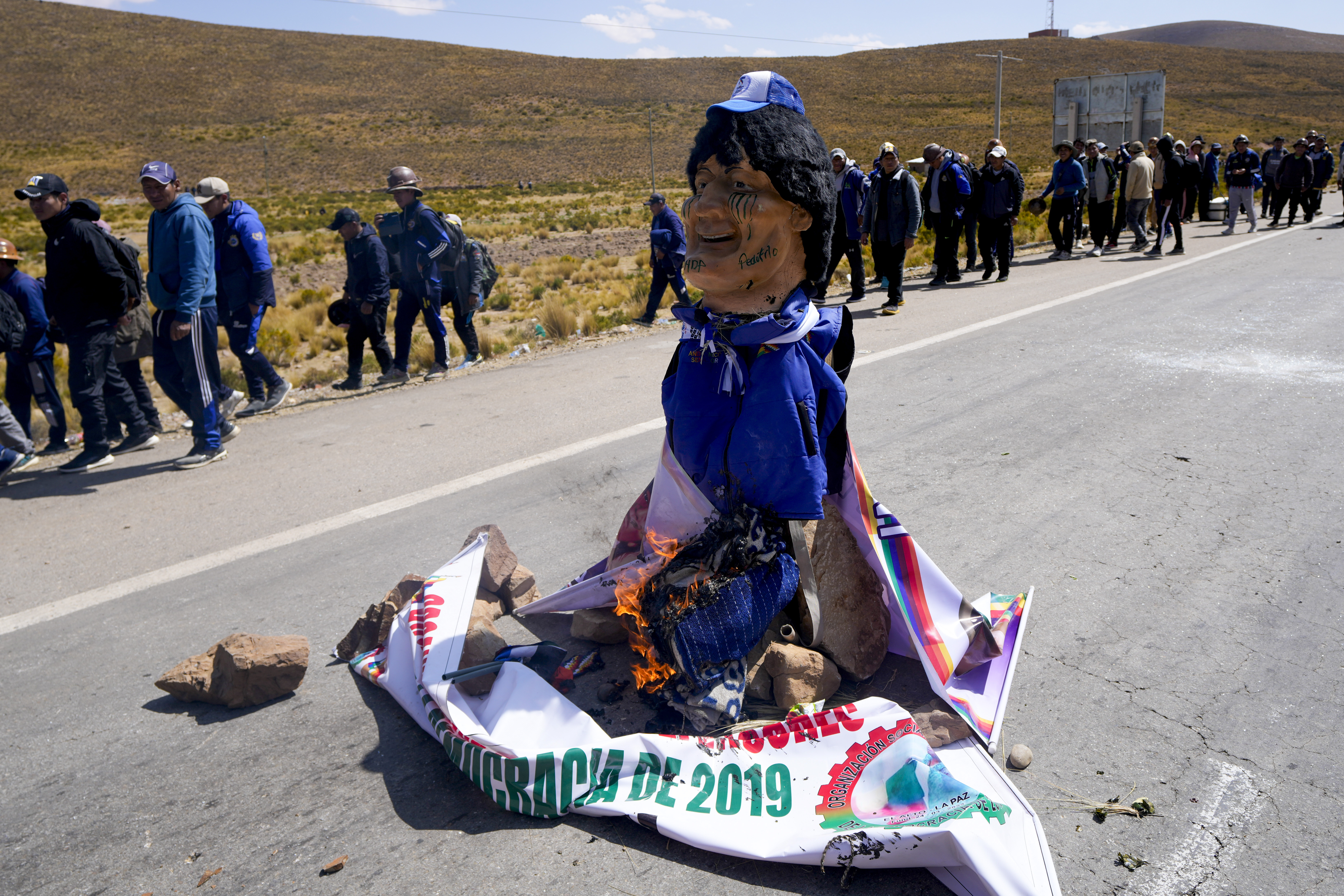 An effigy of former President Evo Morales starts to burn on a road between Caracollo and La Paz, to block Morales supporters who are marching to the capital against the government of President Luis Arce in an escalation of a political dispute between the two politicians, Tuesday, Sept. 17, 2024. (AP Photo/Juan Karita)