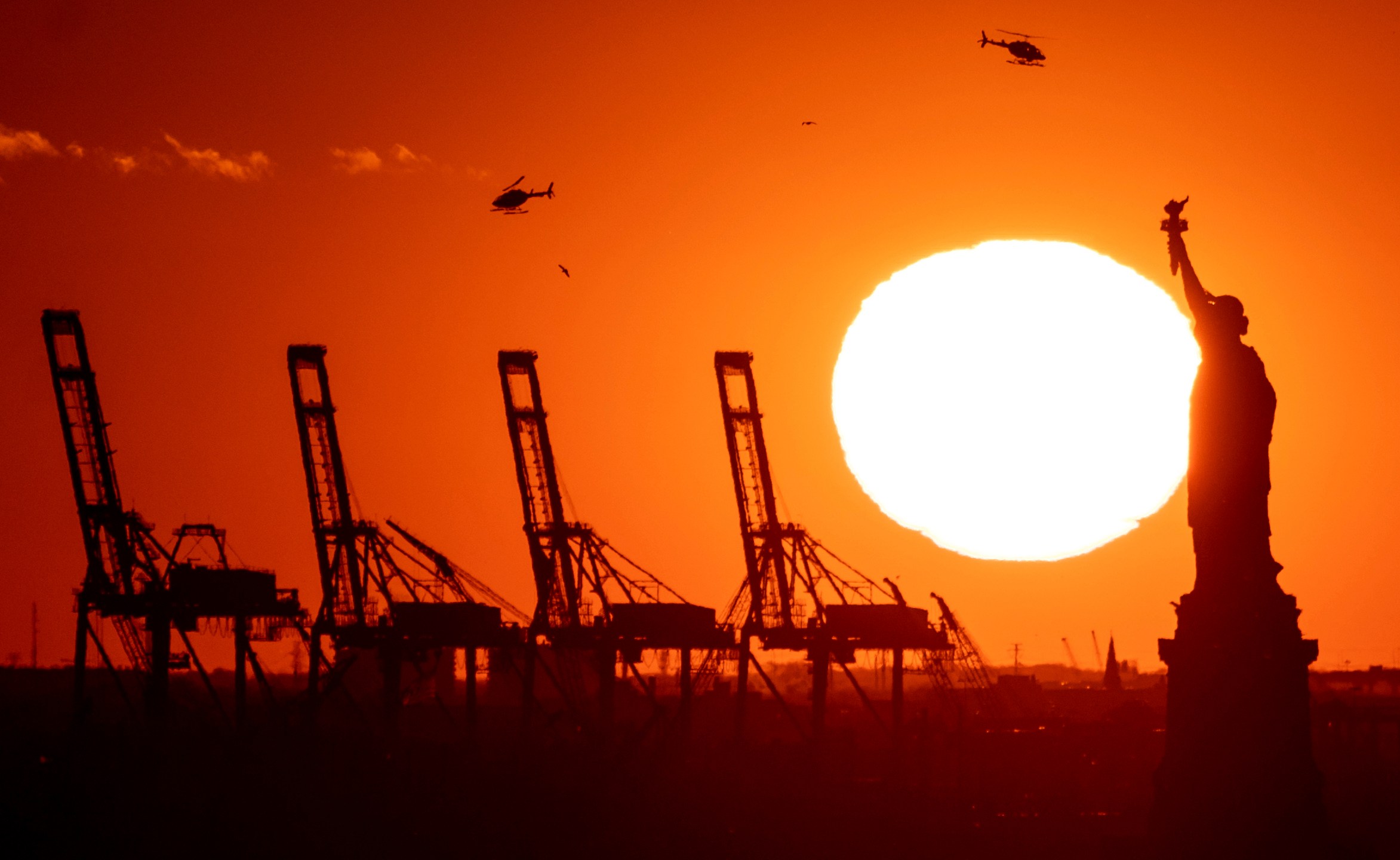 FILE - Cranes at the Port of New York and New Jersey appear behind the Statue of Liberty, Nov. 20, 2022, in a photo taken from New York. (AP Photo/Julia Nikhinson, File)