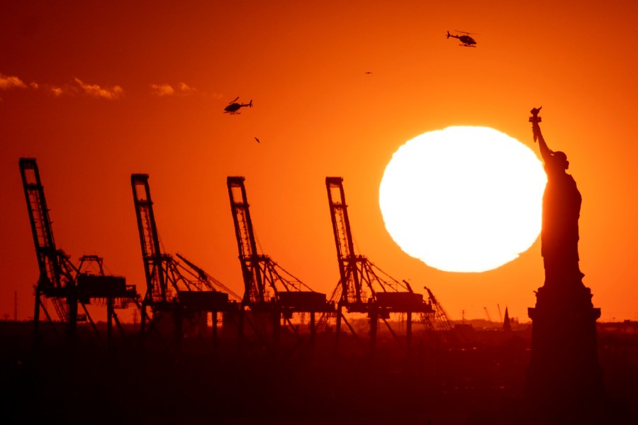 FILE - Cranes at the Port of New York and New Jersey appear behind the Statue of Liberty, Nov. 20, 2022, in a photo taken from New York. (AP Photo/Julia Nikhinson, File)