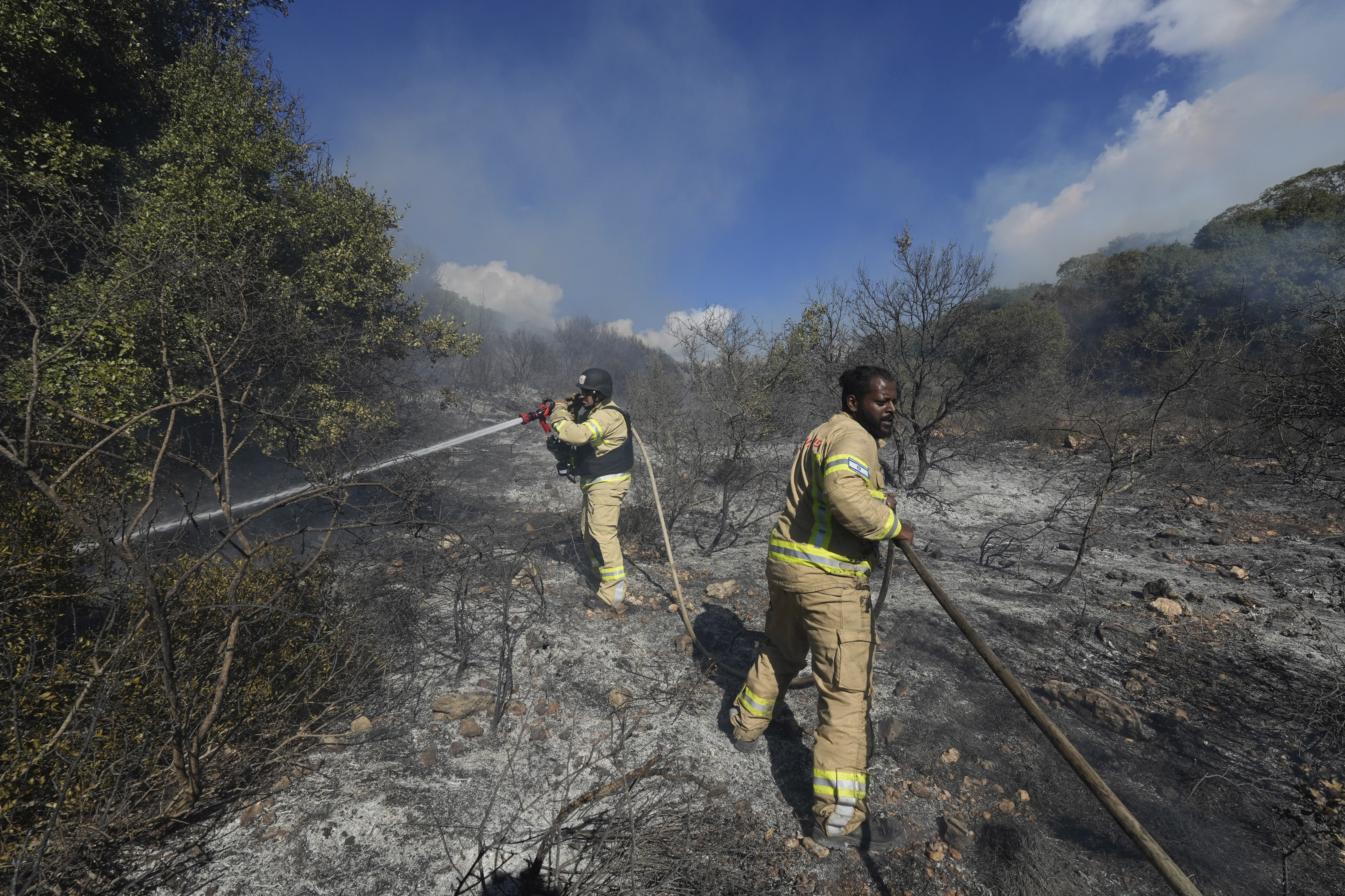 Israeli firefighters work to extinguish a fire after a rocket fired from Lebanon hit an open field in northern Israel, Wednesday, Sept. 18, 2024. (AP Photo/Baz Ratner)