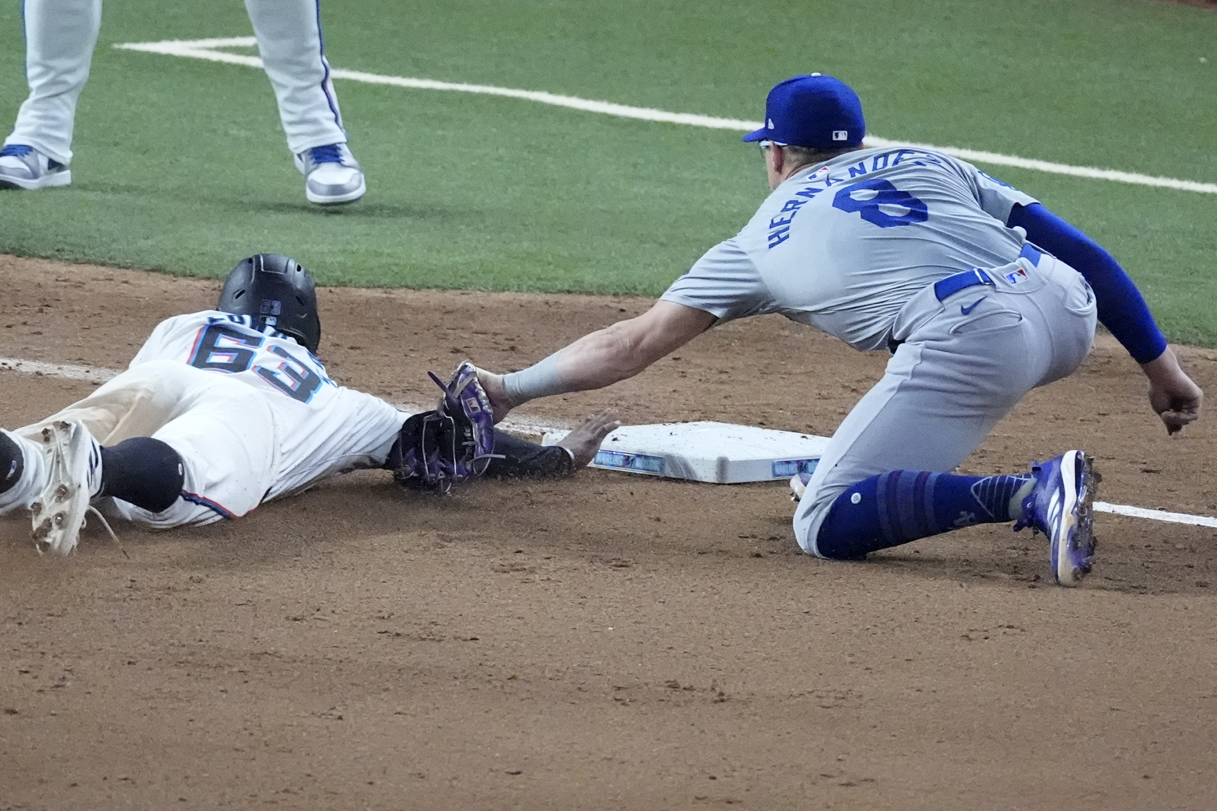 Los Angeles Dodgers third baseman Enrique Hernández (8) tags out Miami Marlins' Xavier Edwards (63) as he dives into third base during the seventh inning of a baseball game, Wednesday, Sept. 18, 2024, in Miami. (AP Photo/Wilfredo Lee)