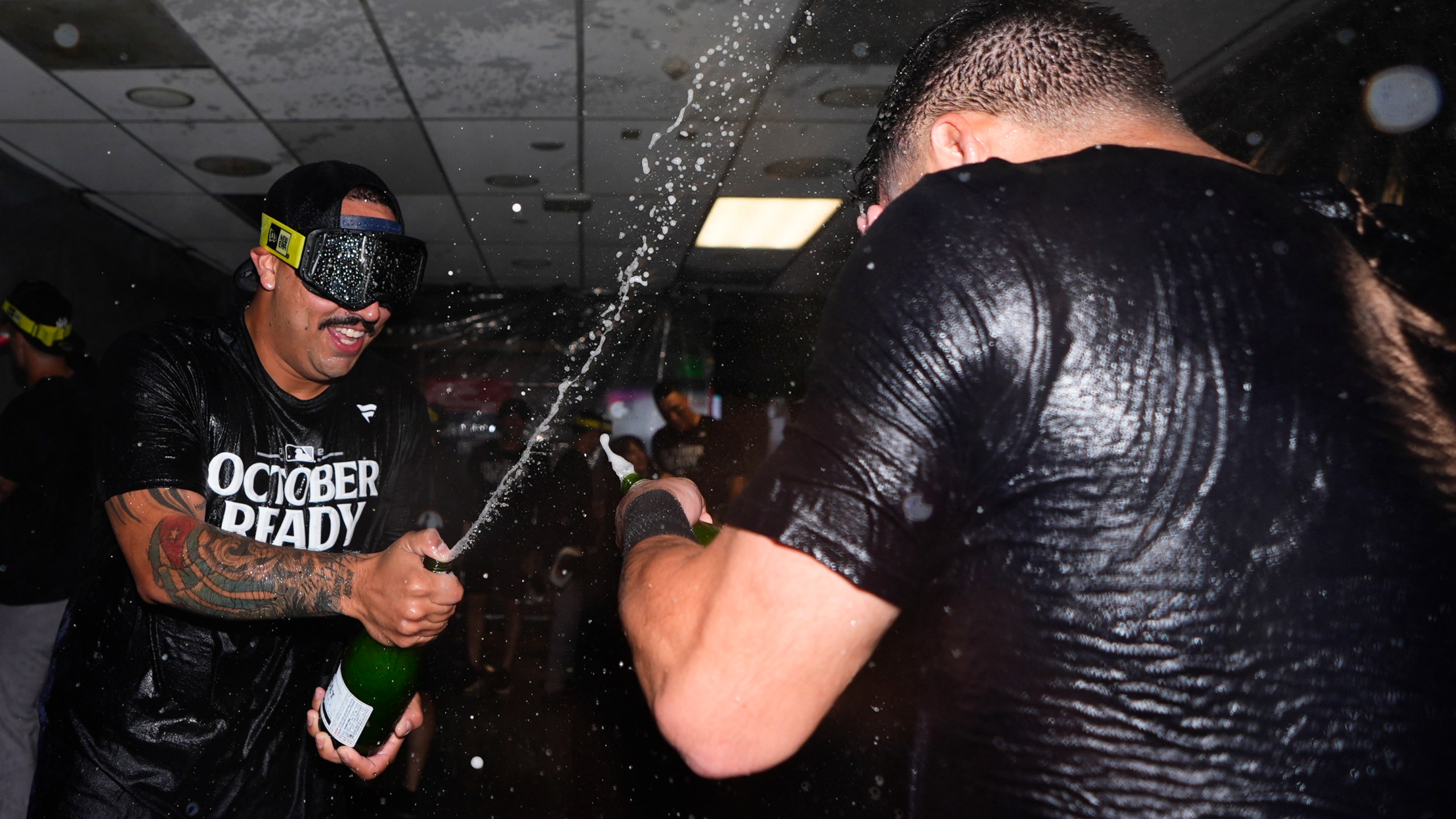 New York Yankees starting pitcher Nestor Cortes, left, sprays champagne on a teammate as they celebrate clinching a playoff spot after a 2-1 win in 10 innings over the Seattle Mariners in a baseball game Wednesday, Sept. 18, 2024, in Seattle. (AP Photo/Lindsey Wasson)