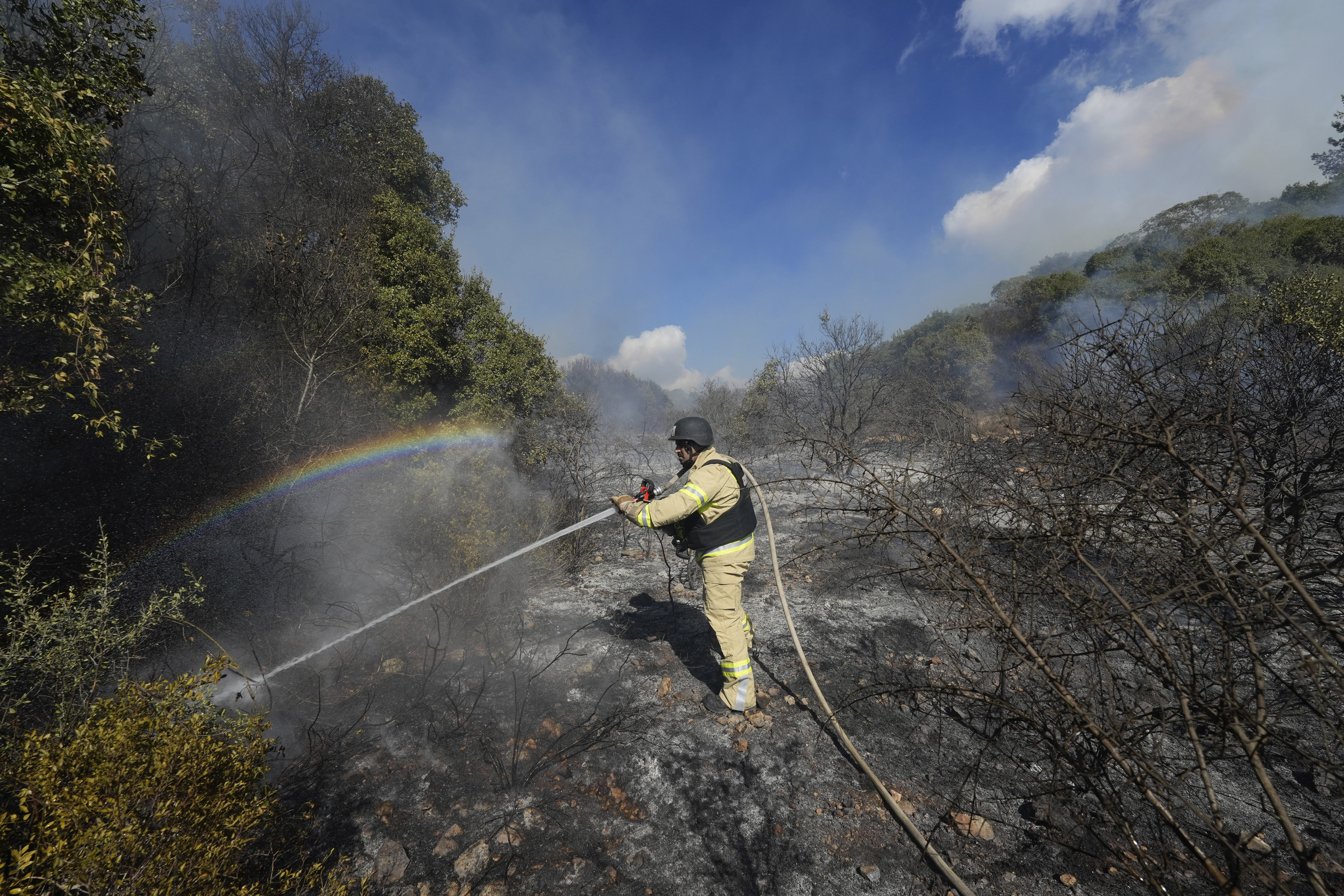 An Israeli firefighter works to extinguish a fire after a rocket fired from Lebanon hit an open field in northern Israel, Wednesday, Sept. 18, 2024. (AP Photo/Baz Ratner)