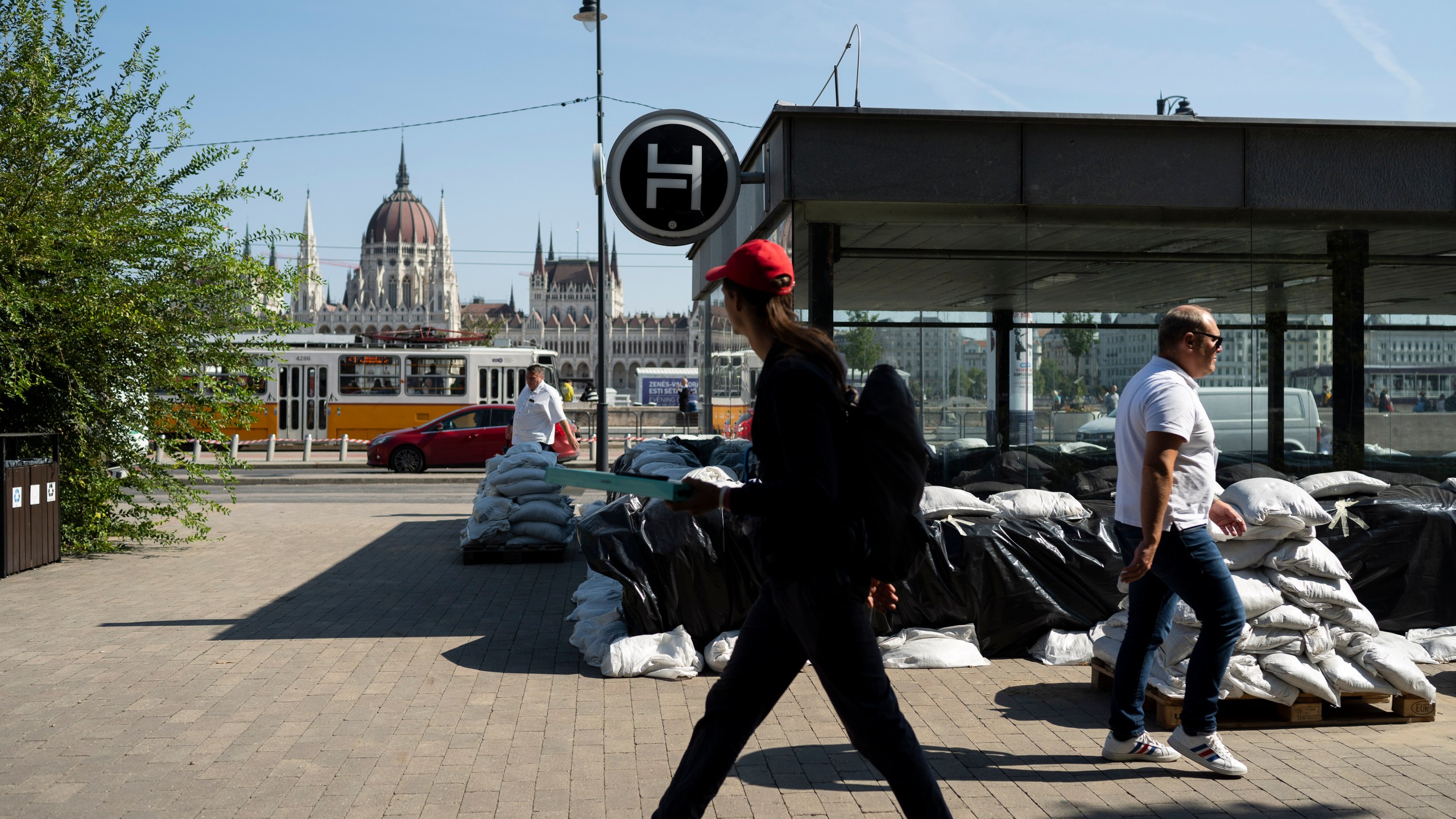 People walk by a metro station protected by sandbags as the Danube river floods it's banks, central Budapest, Hungary, Thursday, Sept. 19, 2024. (AP Photo/Denes Erdos)