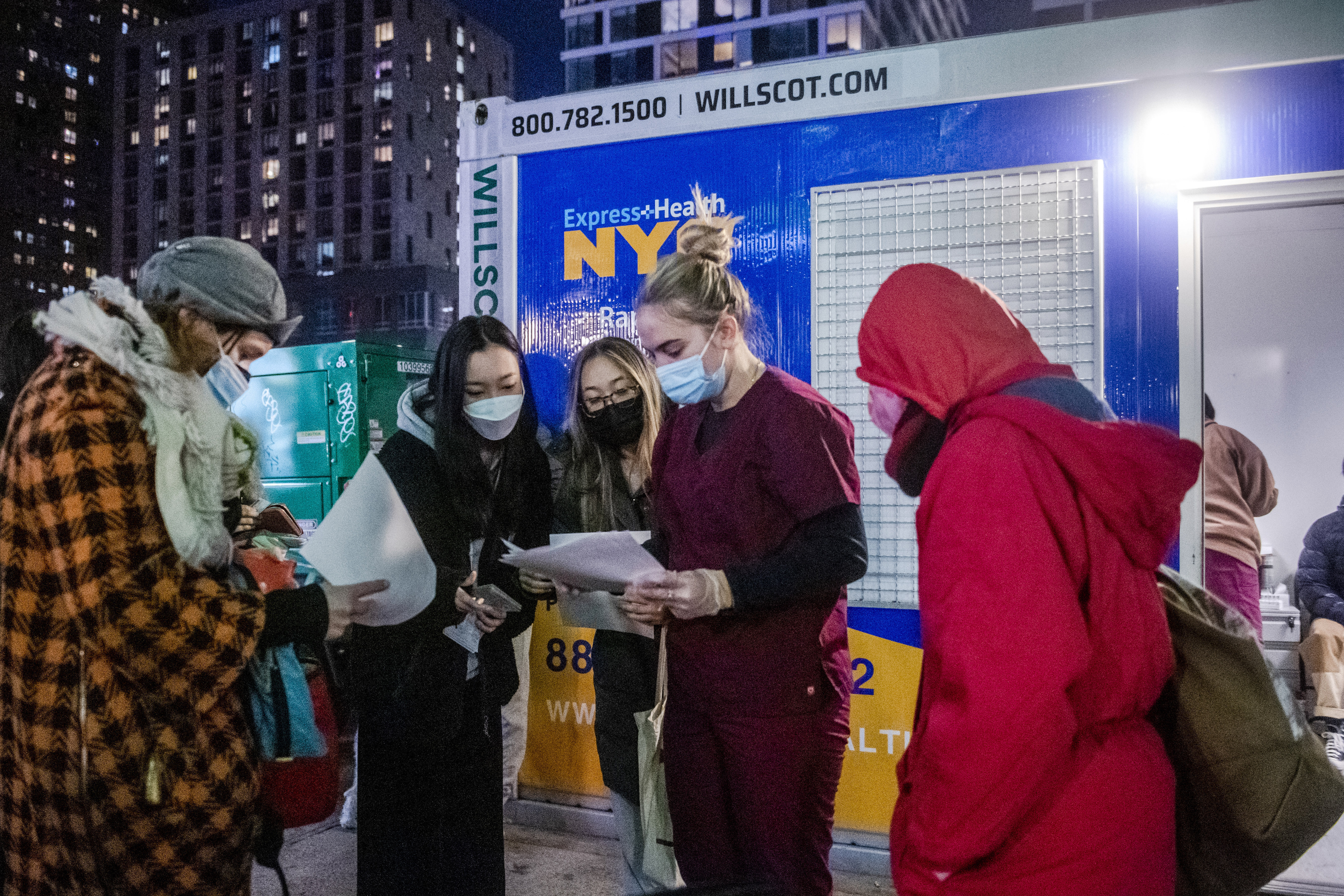 FILE - People check their rapid COVID-19 test results outside of a testing site on the Lower East Side of Manhattan, on Dec. 21, 2021, in New York. (AP Photo/Brittainy Newman, File)