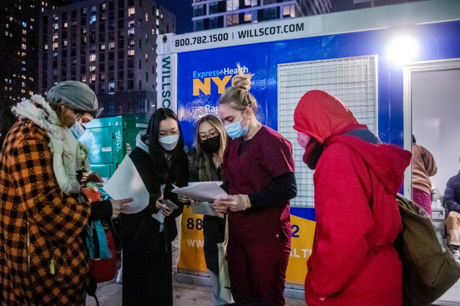 FILE - People check their rapid COVID-19 test results outside of a testing site on the Lower East Side of Manhattan, on Dec. 21, 2021, in New York. (AP Photo/Brittainy Newman, File)