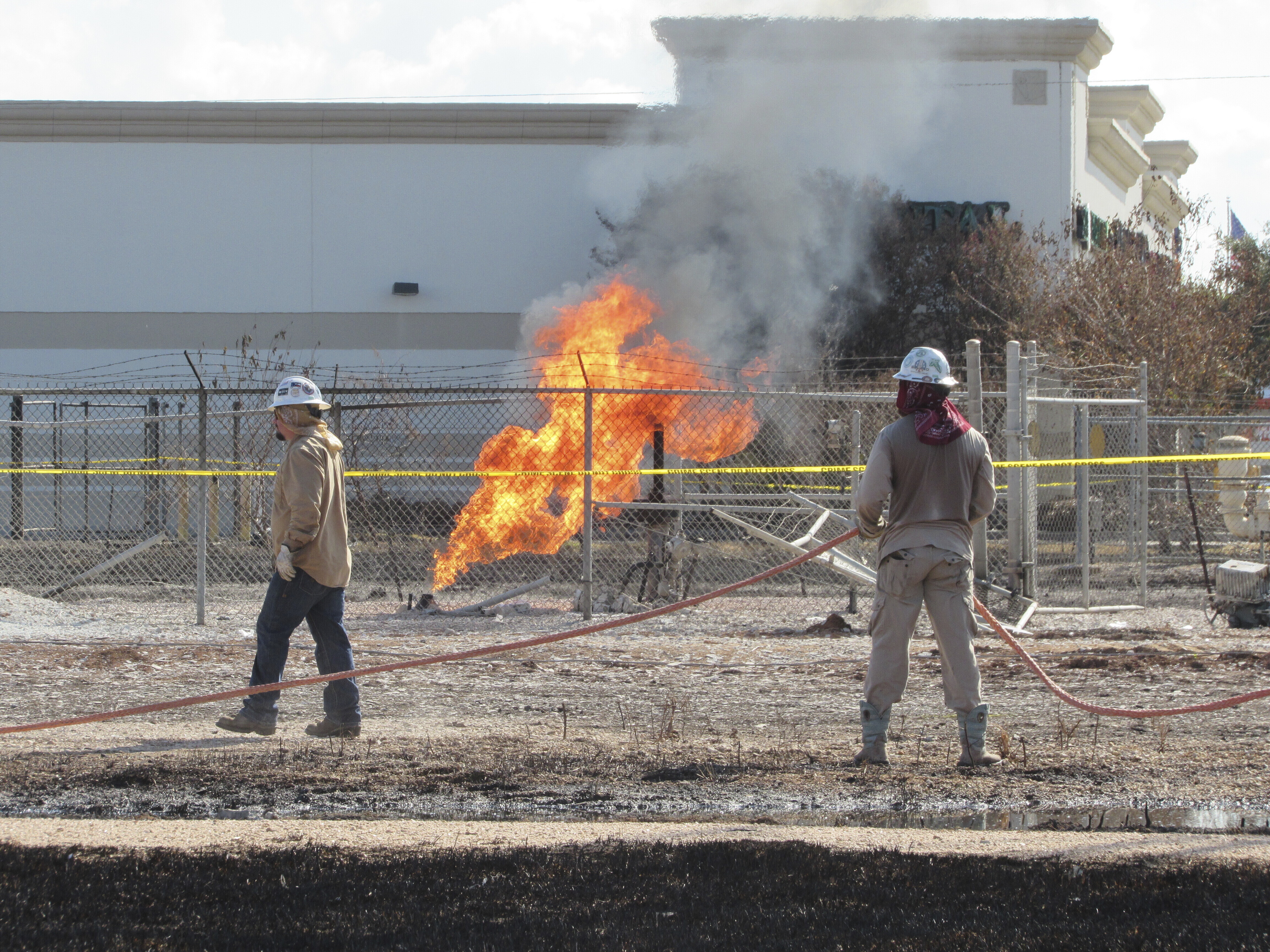 Workers stand near a pipeline fire in Deer Park, Texas, on Thursday, Sept. 19, 2024. The fire had dramatically shrunk in size since it began on Monday, Sept. 16, 2024, and officials said they expected it to be extinguished sometime Thursday evening. (AP Photo/Juan A. Lozano)