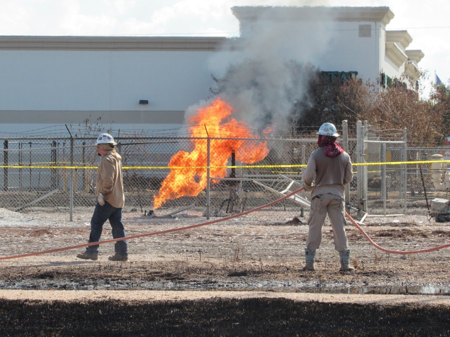 Workers stand near a pipeline fire in Deer Park, Texas, on Thursday, Sept. 19, 2024. The fire had dramatically shrunk in size since it began on Monday, Sept. 16, 2024, and officials said they expected it to be extinguished sometime Thursday evening. (AP Photo/Juan A. Lozano)