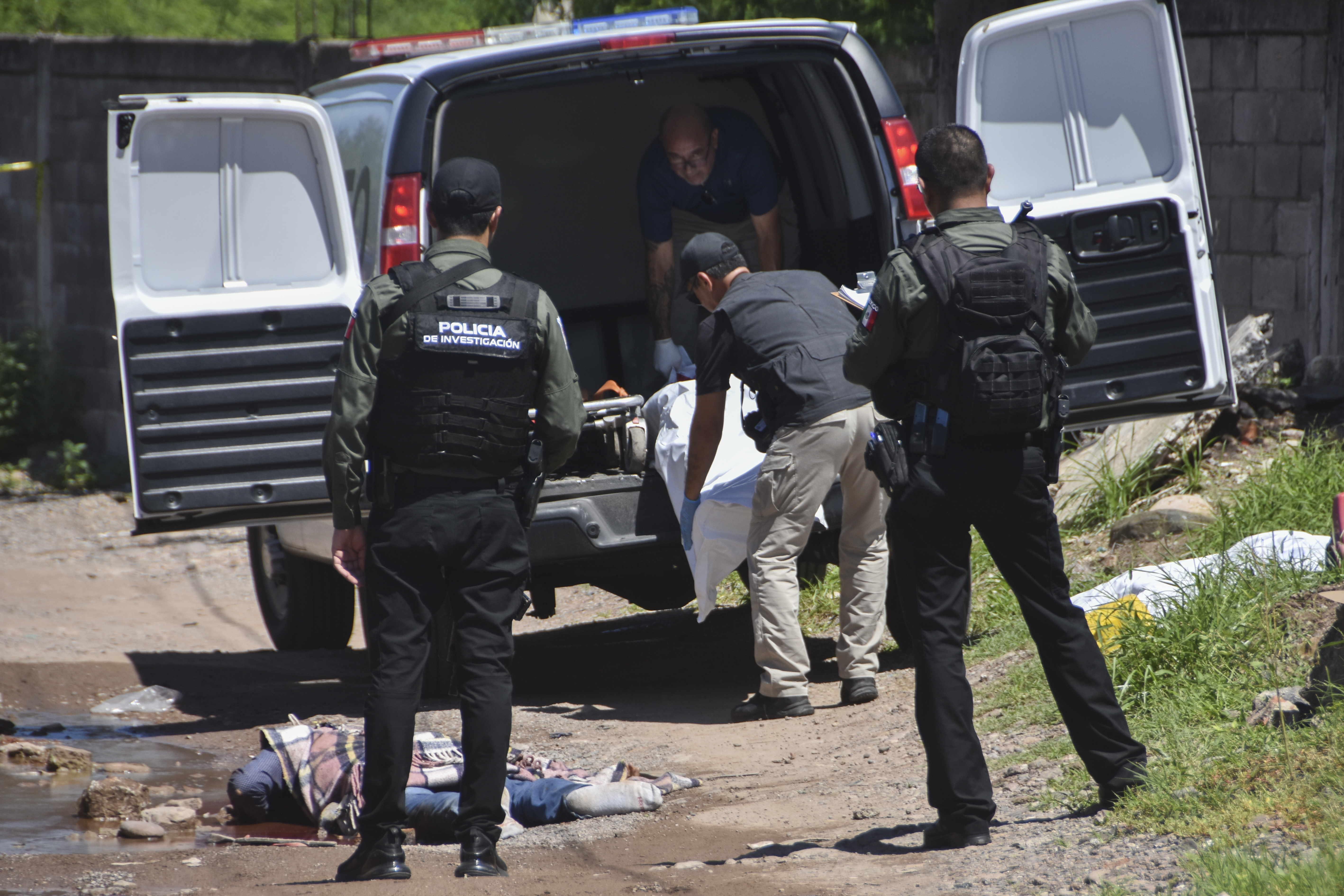 Police watch forensics remove bodies from a street in Culiacan, Sinaloa state, Mexico, Tuesday, Sept. 17, 2024. (AP Photo)