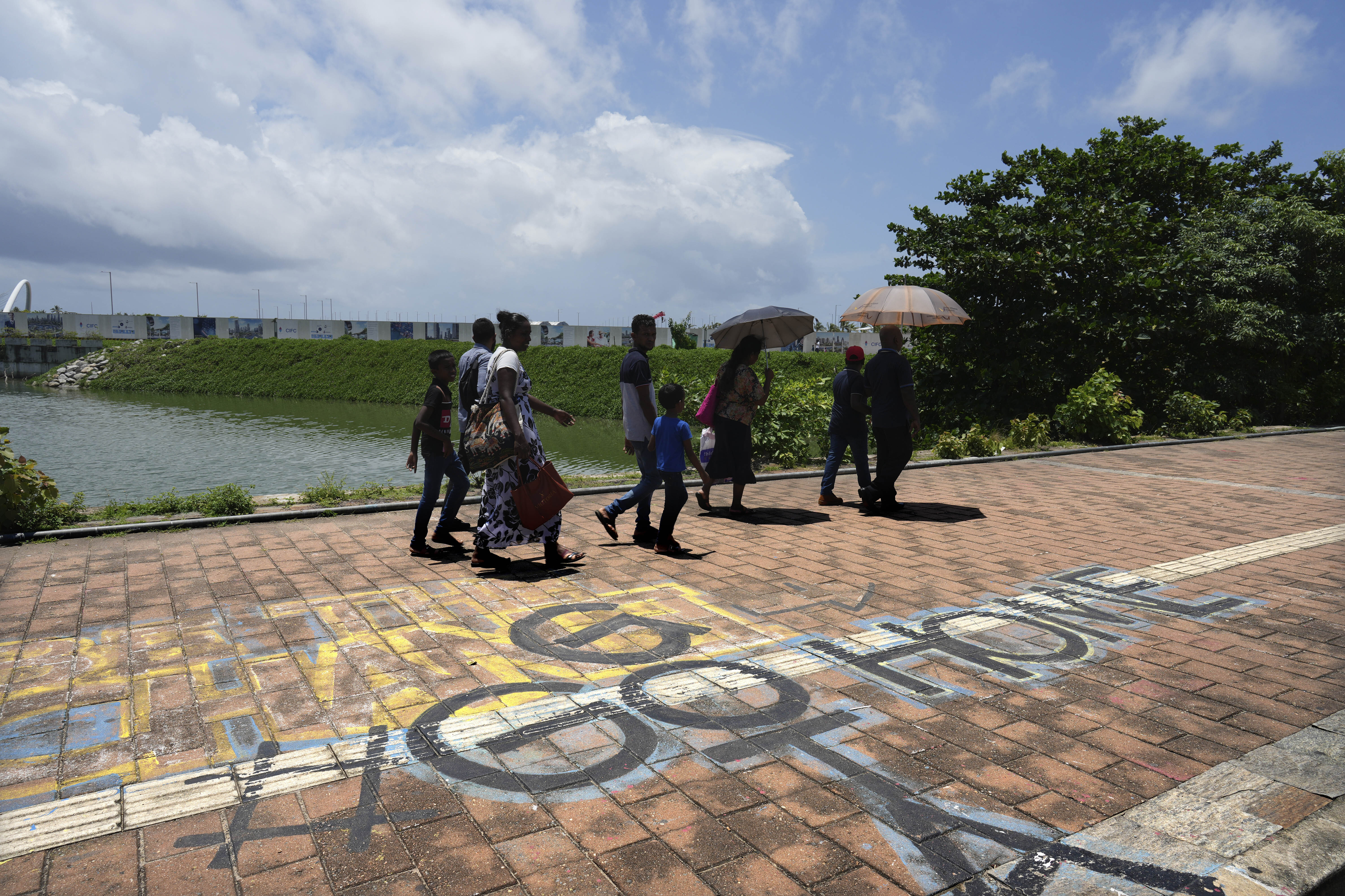 People walk past a graffiti near the 2022 protest site that reads "Go Home Gota," a slogan under which Sri Lankans where mobilized during the public uprising that led to the ousting of the then president Gotabaya Rajapaksa, in Colombo, Sri Lanka, Monday, Sept. 16, 2024. (AP Photo/Rajesh Kumar Singh)