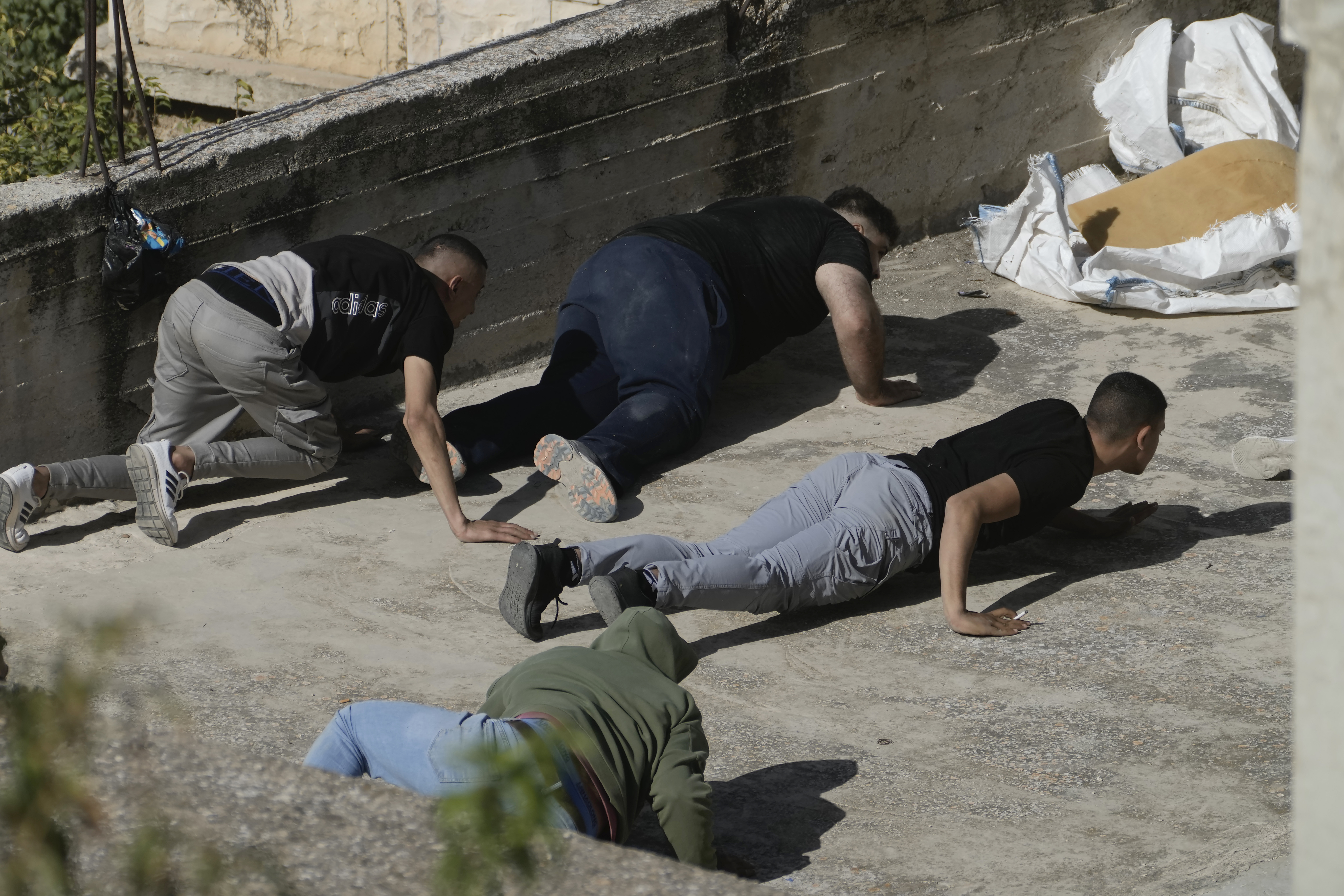 Palestinians duck for cover as the Israeli army raided the northern West Bank town of Qabatiya on Thursday, Sept.19, 2024. (AP Photo/Majdi Mohammed)