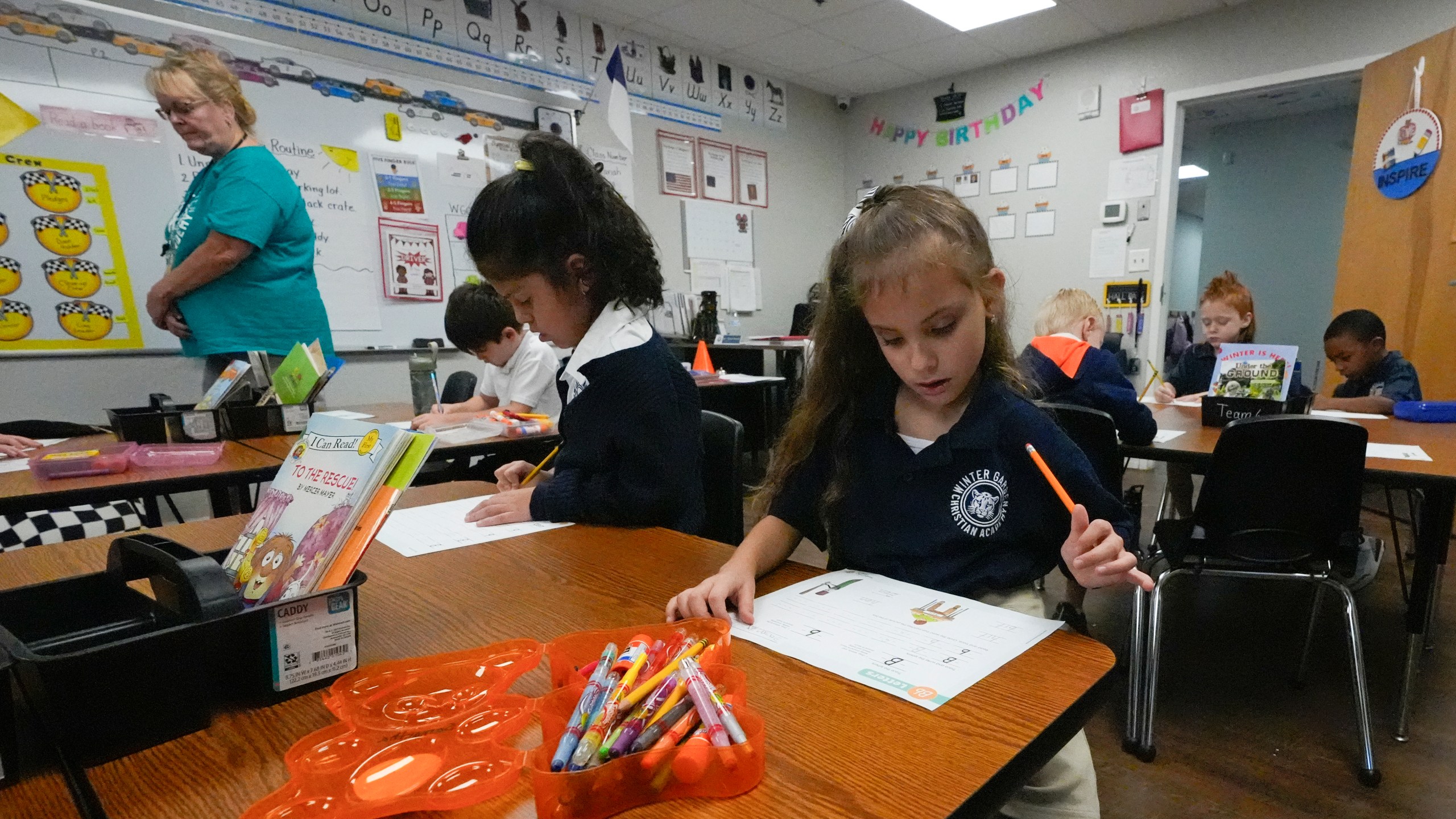 First grade teacher Sharon Parsons, back left, checks on students working in the classroom at the Winter Garden Christian Academy Thursday, Aug. 29, 2024, in Winter Garden, Fla. (AP Photo/John Raoux)