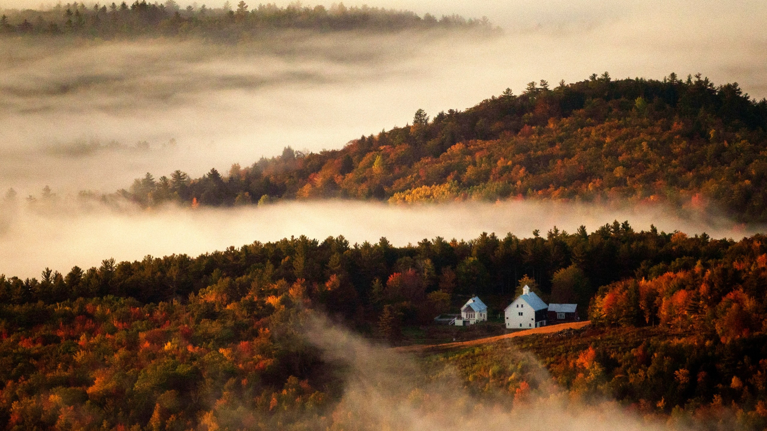 FILE - Valley fog wafts through the autumn-colored hills near the Picket Hill Farm, Wednesday morning, Oct. 13, 2021, in Denmark, Maine. (AP Photo/Robert F. Bukaty, File)