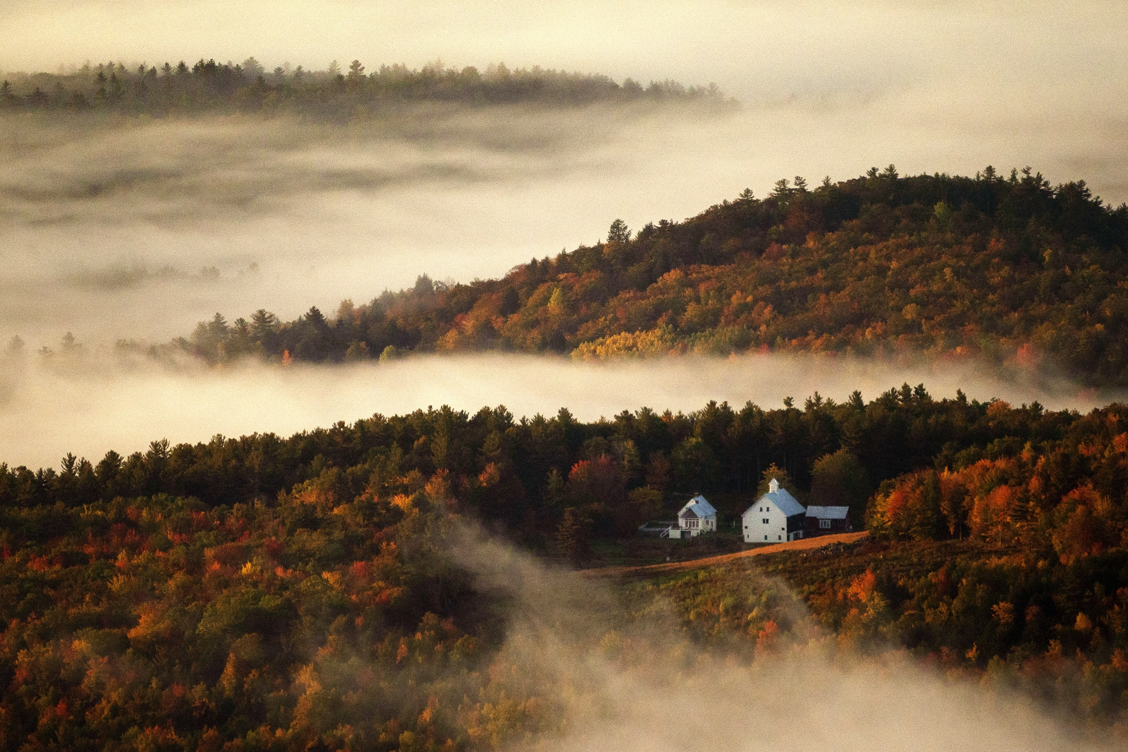 FILE - Valley fog wafts through the autumn-colored hills near the Picket Hill Farm, Wednesday morning, Oct. 13, 2021, in Denmark, Maine. (AP Photo/Robert F. Bukaty, File)