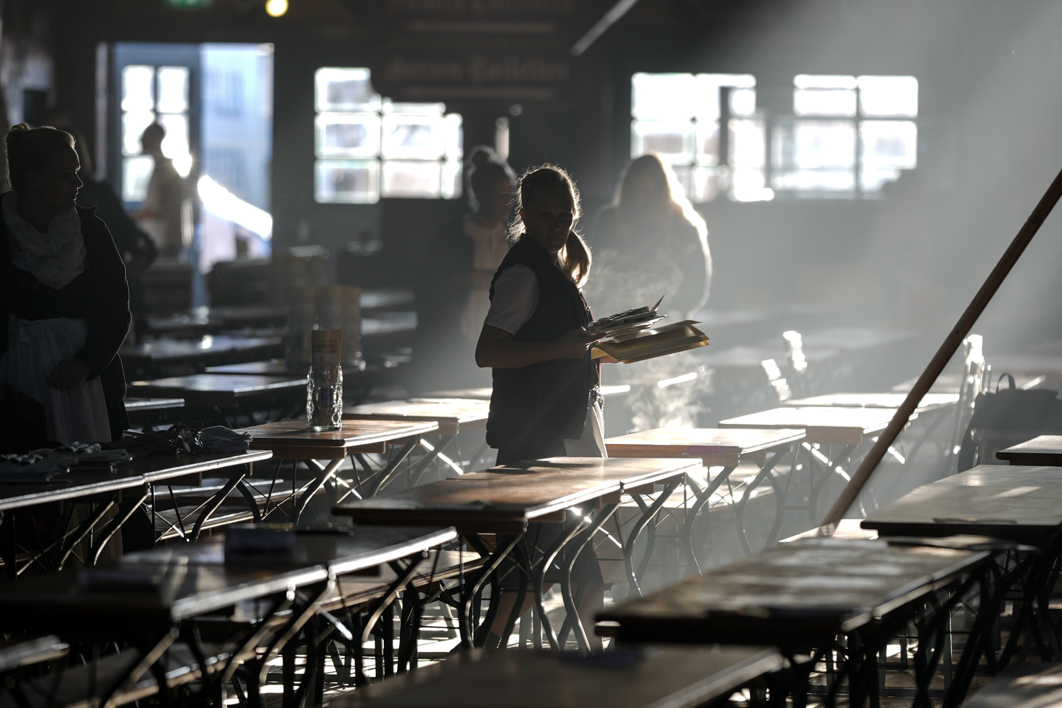 A waitress prepares tables in a marquee for the start of the 189th 'Oktoberfest' beer festival in Munich, Germany, early Saturday morning, Sept. 21, 2024. (AP Photo/Matthias Schrader)