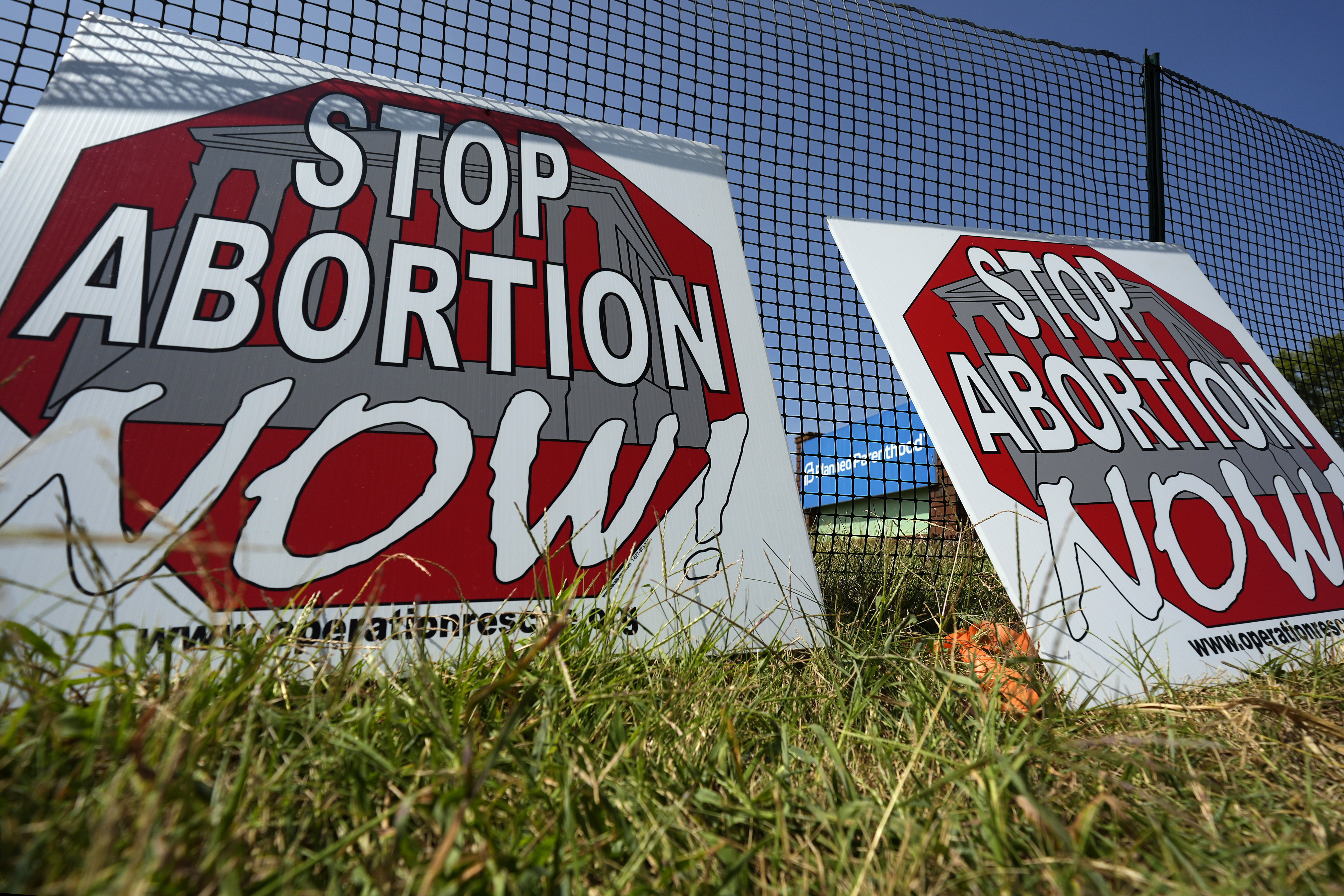 Anti-abortion signs lean agains a fence outside a recently opened Planned Parenthood clinic in Pittsburg, Kan., Tuesday, Sept. 10, 2024. (AP Photo/Charlie Riedel)