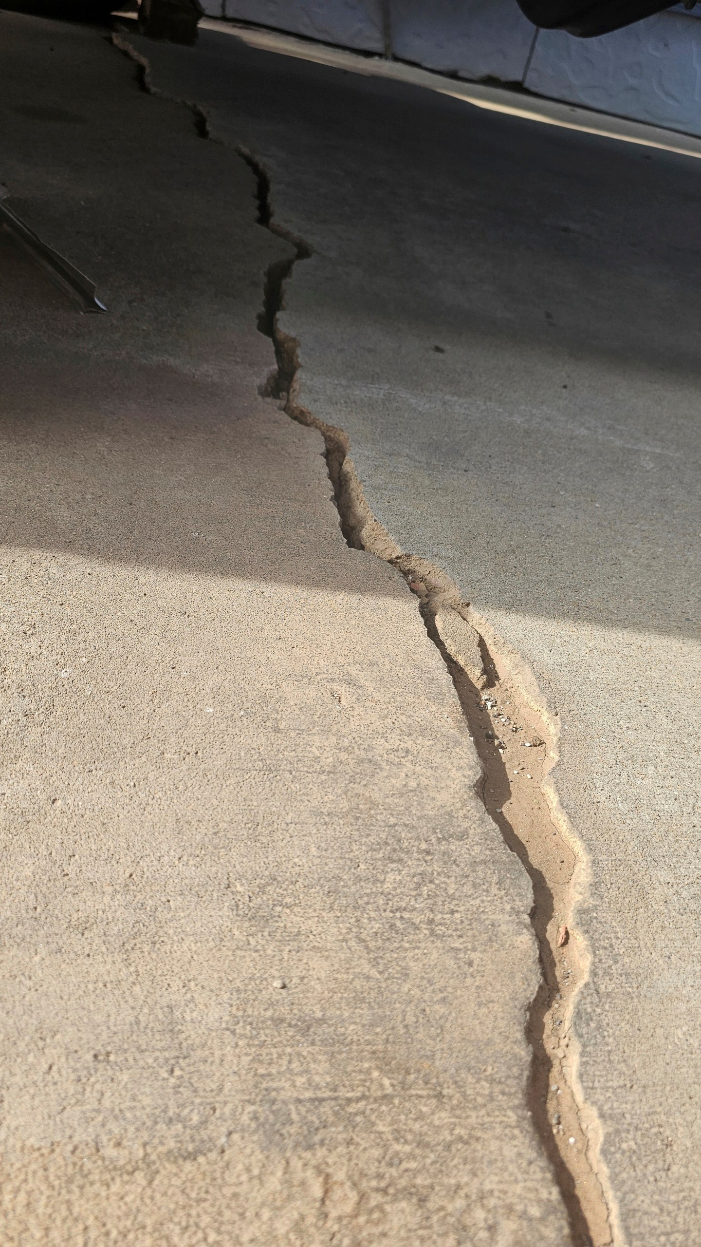 This photo taken April 27, 2022, by Tonya Junker shows a crack on the sidewalk from a sinkhole in the Hideaway Hills neighborhood near Rapid City, S.D. (Tonya Junker via AP)