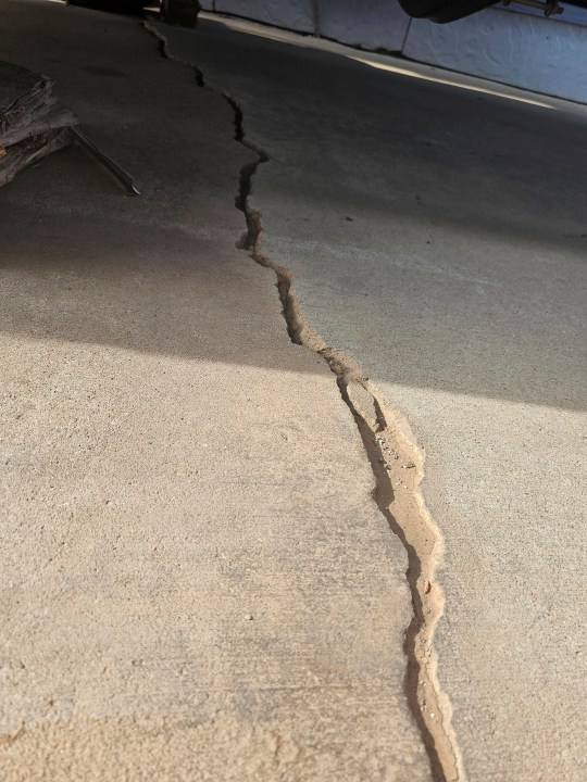 This photo taken April 27, 2022, by Tonya Junker shows a crack on the sidewalk from a sinkhole in the Hideaway Hills neighborhood near Rapid City, S.D. (Tonya Junker via AP)