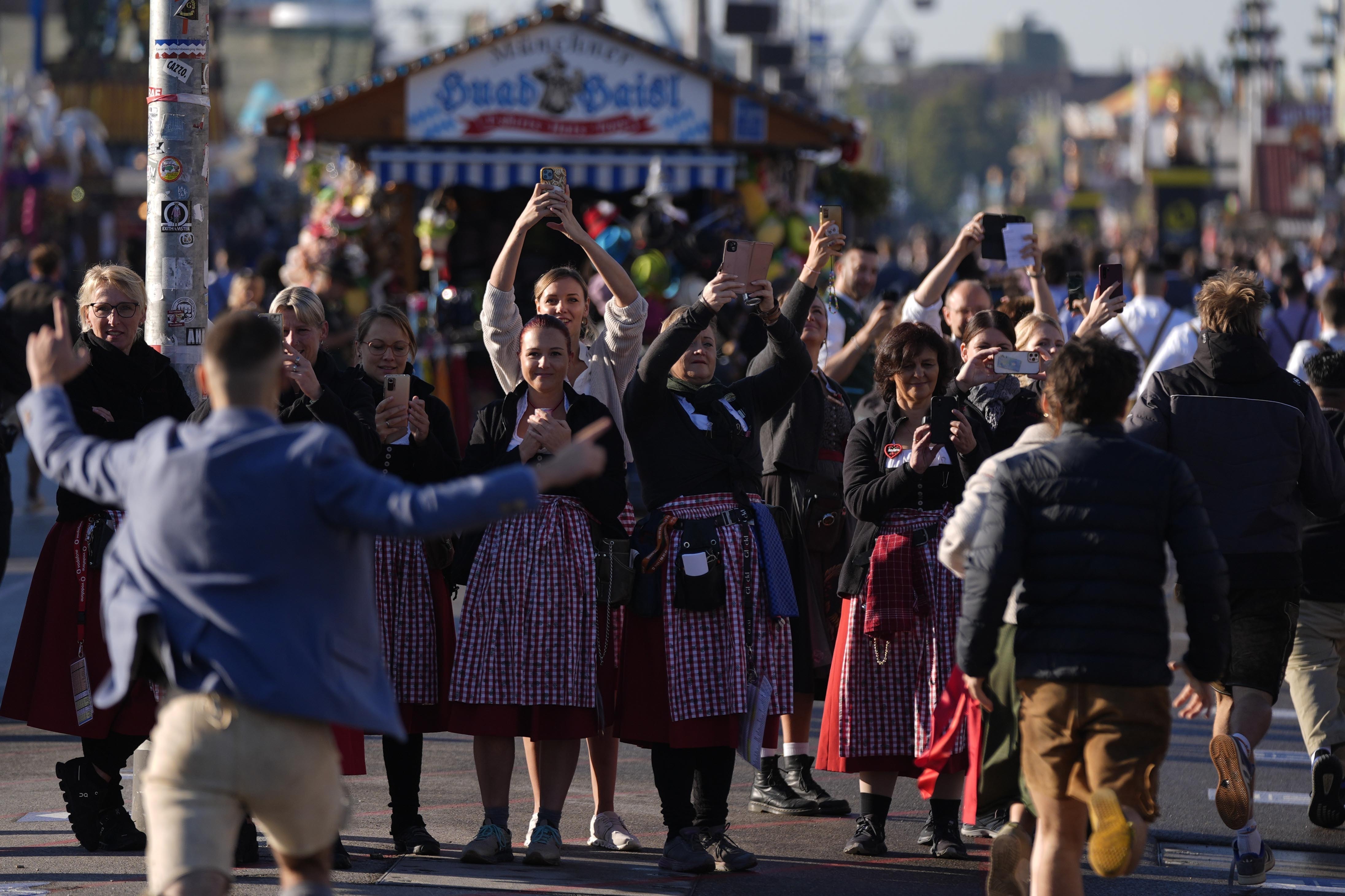 Waitresses film the opening start of the 189th 'Oktoberfest' beer festival in Munich, Germany, Saturday, Sept. 21, 2024. (AP Photo/Matthias Schrader)