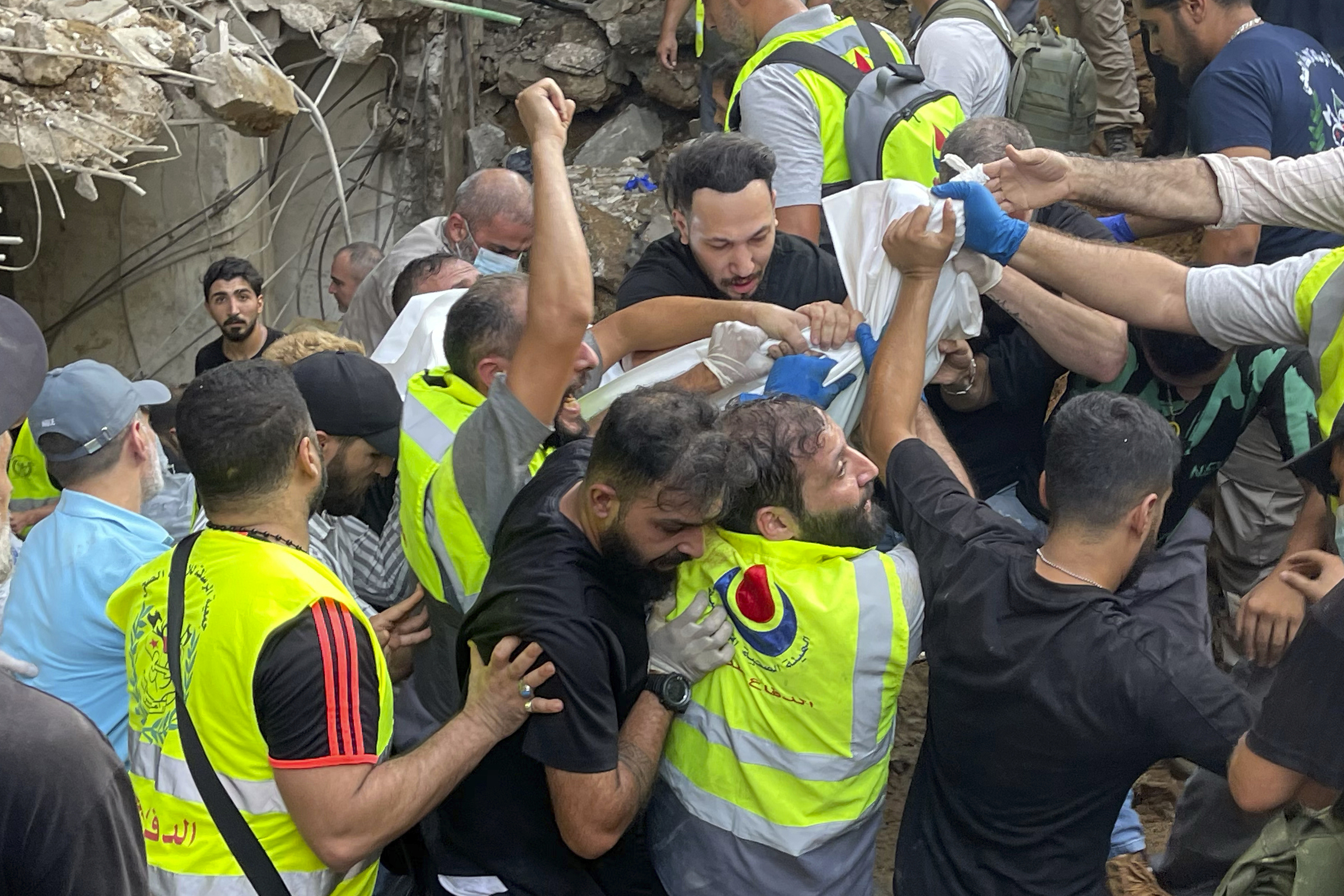 Rescuers carry a body at the scene of a missile strike in the southern suburbs of Beirut, Friday, Sept. 20, 2024. (AP Photo/Bilal Hussein)