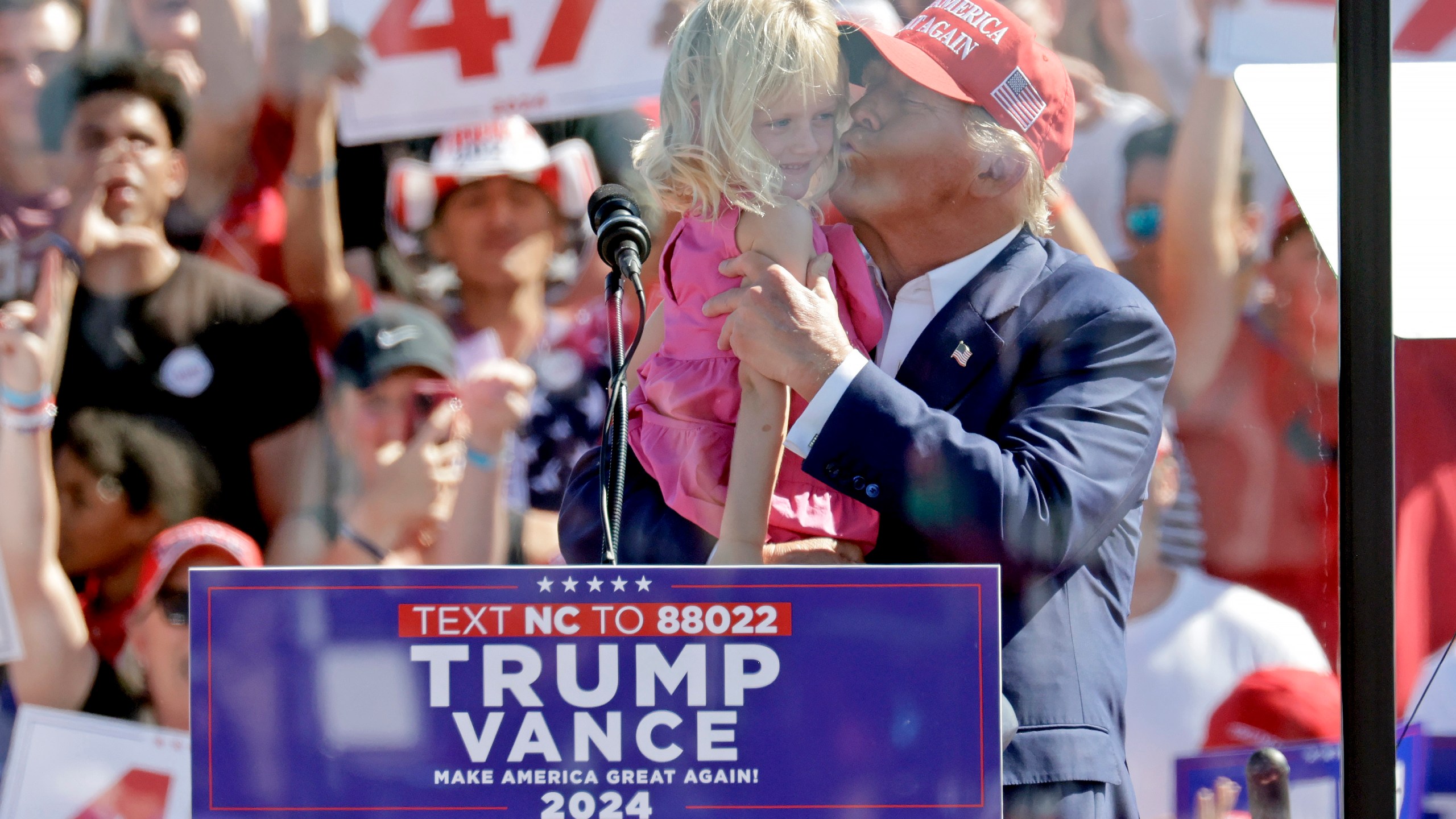 Republican presidential nominee former President Donald Trump kisses his granddaughter Carolina Trump as he speaks at a campaign event at Wilmington International Airport in Wilmington, N.C., Saturday, Sept. 21, 2024. (AP Photo/Chris Seward)