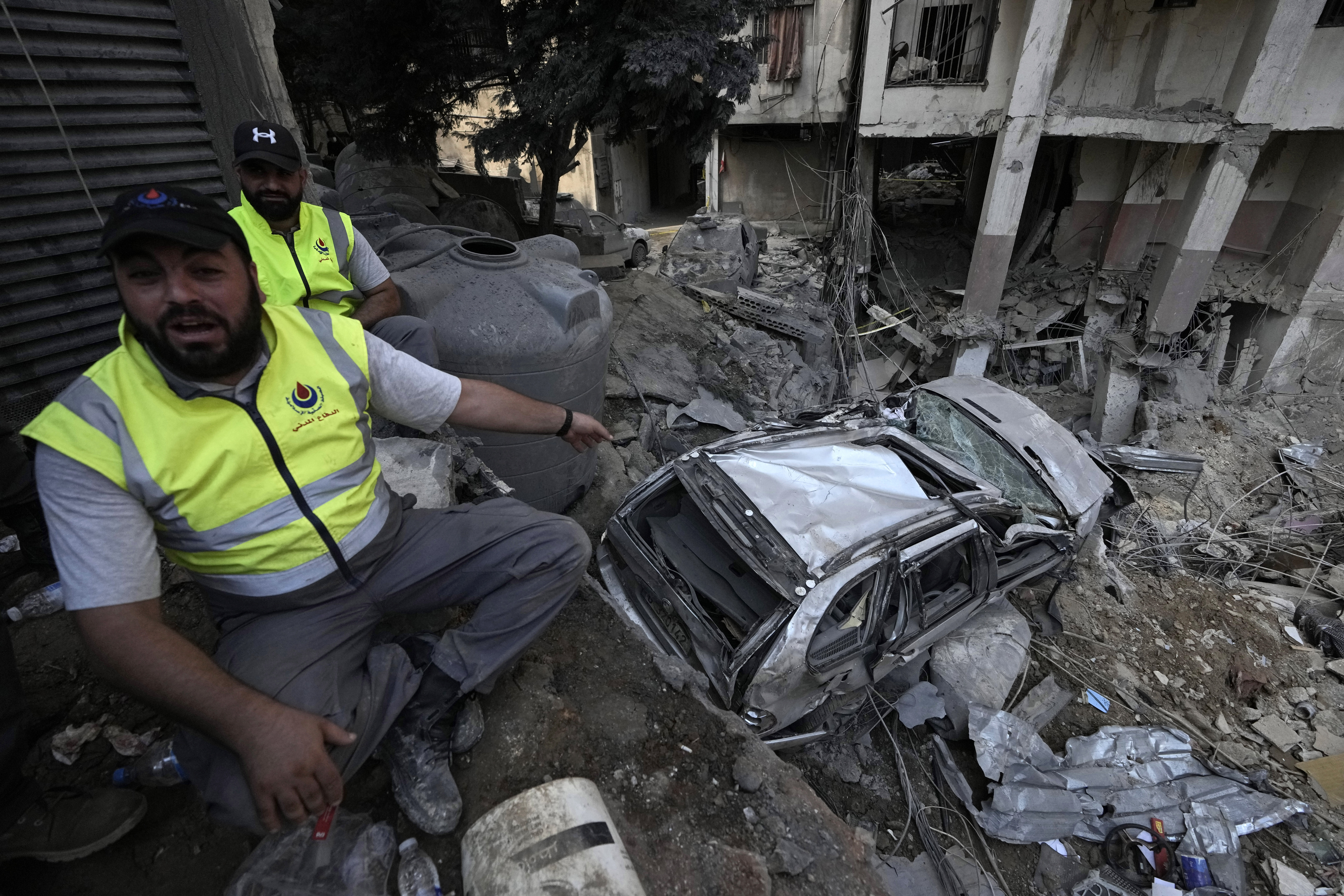 A rescuers gestures near a damaged car at the site of Friday's Israeli strike in Beirut's southern suburbs, Saturday, Sept. 21, 2024. (AP Photo/Bilal Hussein)